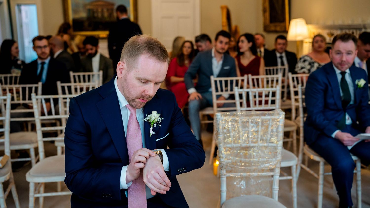 White chairs lined up for a wedding ceremony in an elegant indoor venue.