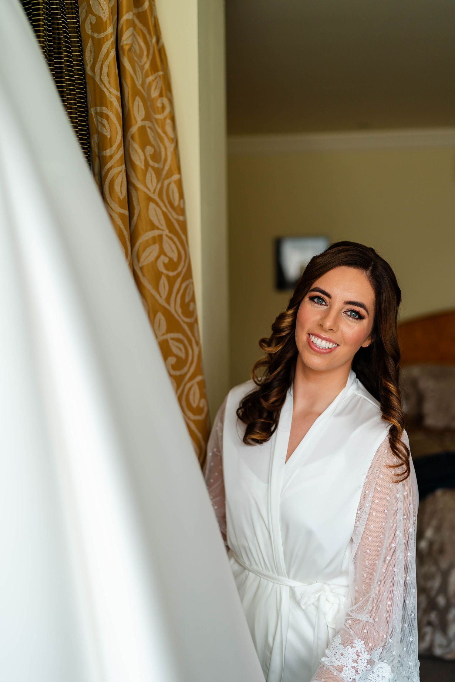 Getting ready scene with white bridal robe and wedding dress in background.