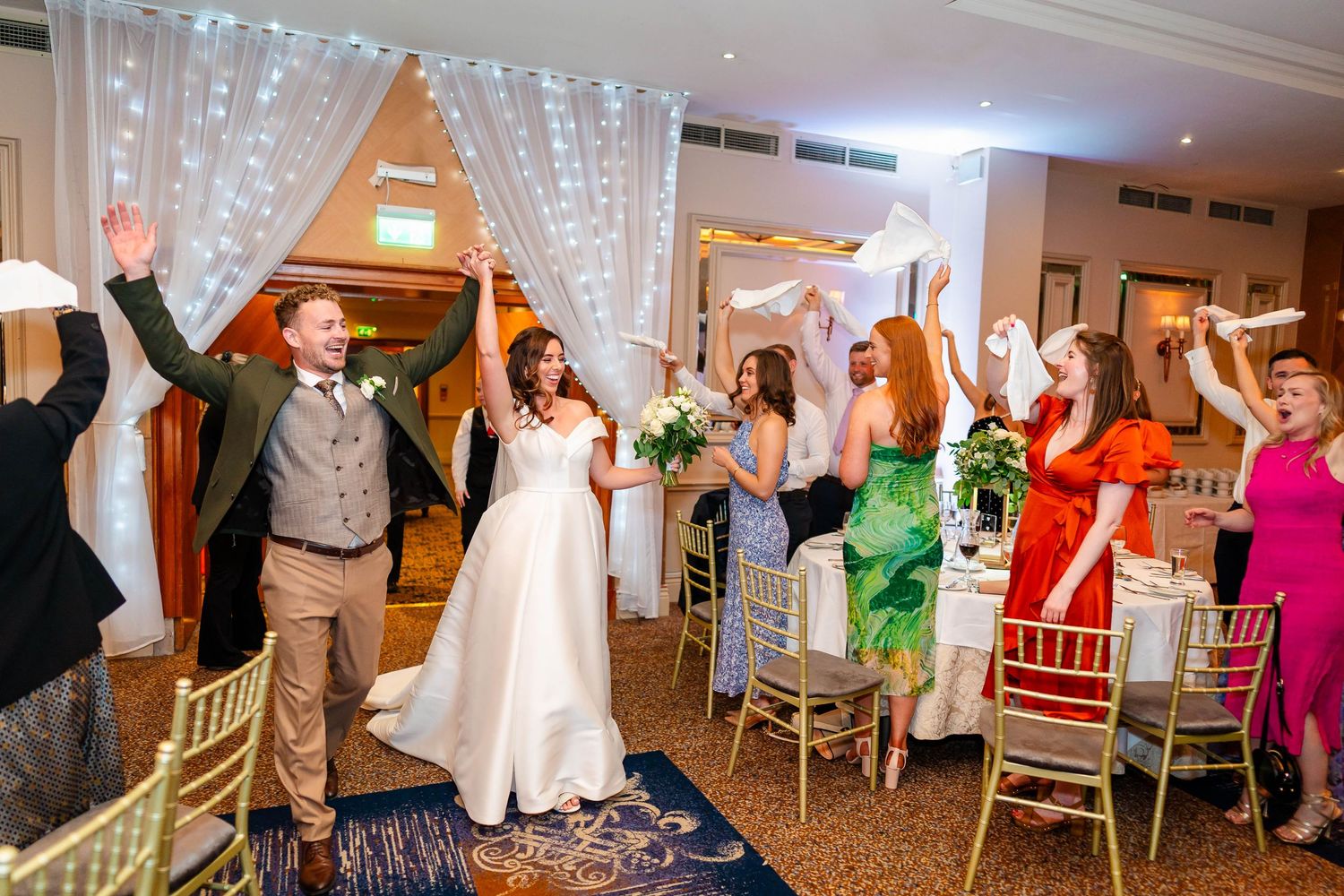 Wedding reception dance floor with hanging string lights and guests celebrating.