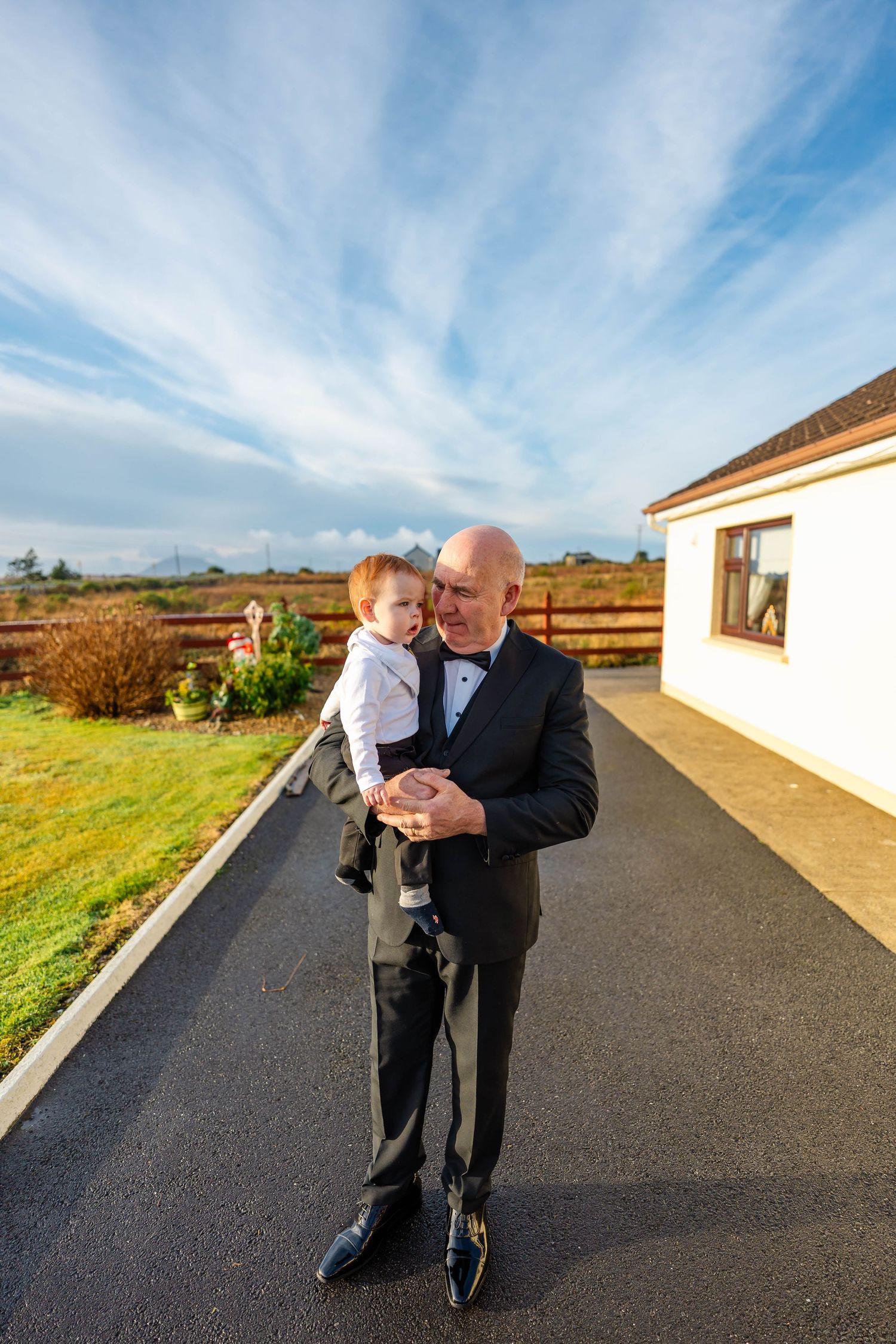 Couple dancing on a paved pathway with scenic rural landscape in the background.
