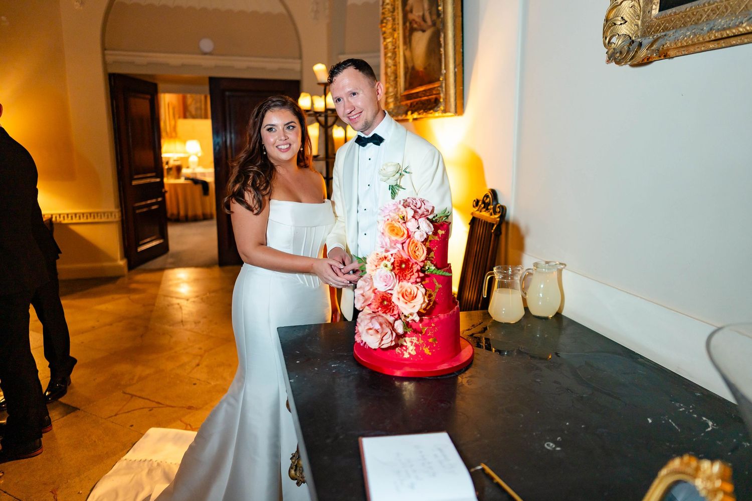 A couple in formal wedding attire dance together in a warmly lit reception venue.