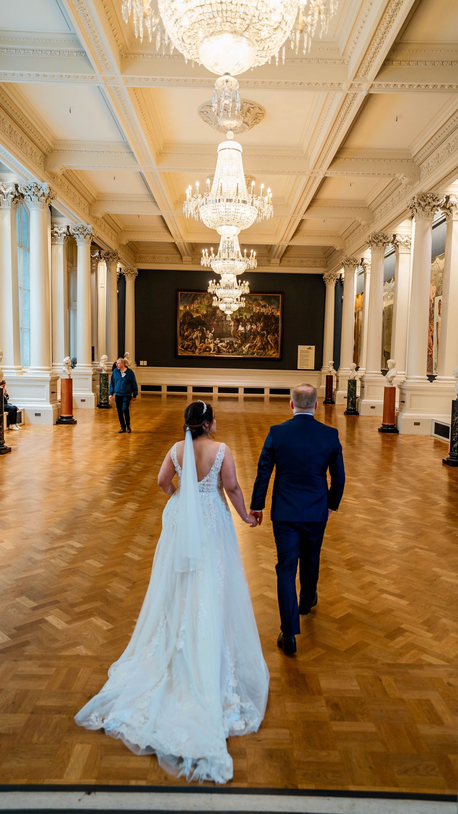 Grand ballroom with crystal chandeliers and detailed crown molding featuring herringbone wood floors.