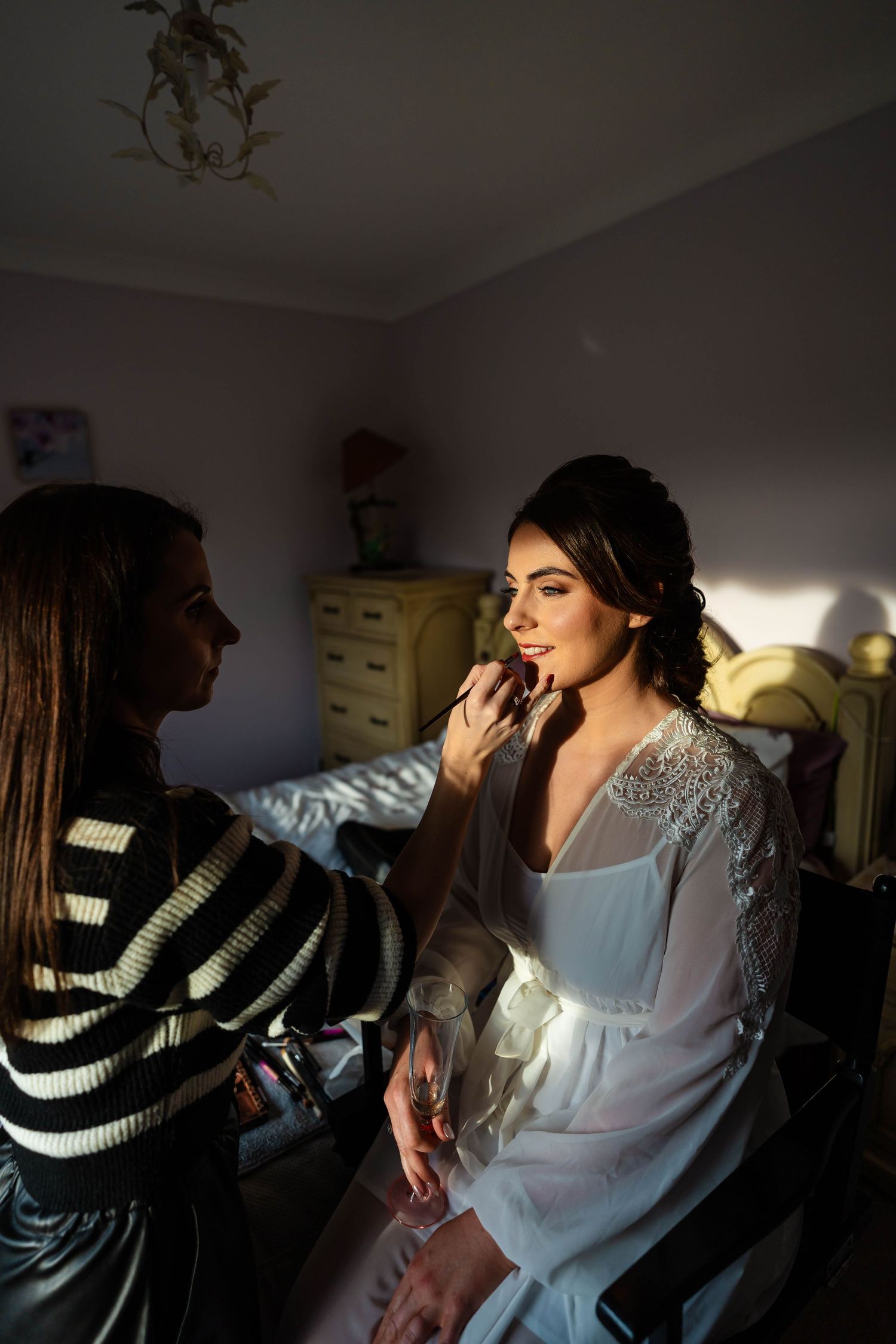 Wedding preparation scene in a dimly lit room with natural window light.