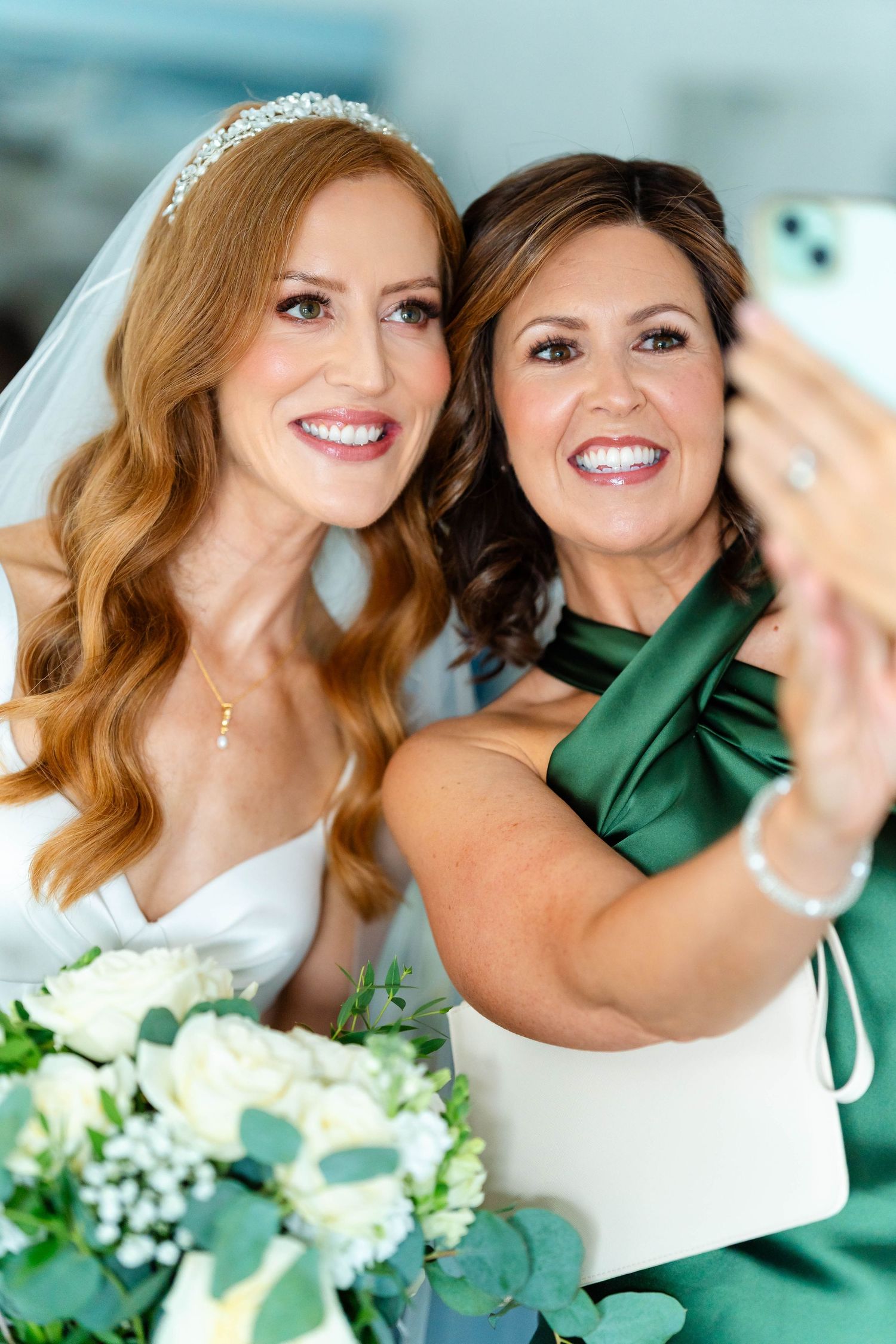 Joyful wedding party taking selfies with white and green floral bouquets.