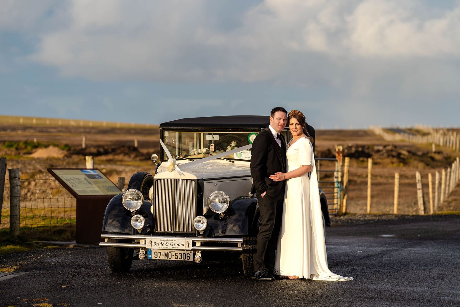 Classic vintage car adds elegance to outdoor wedding photos on a rural road.