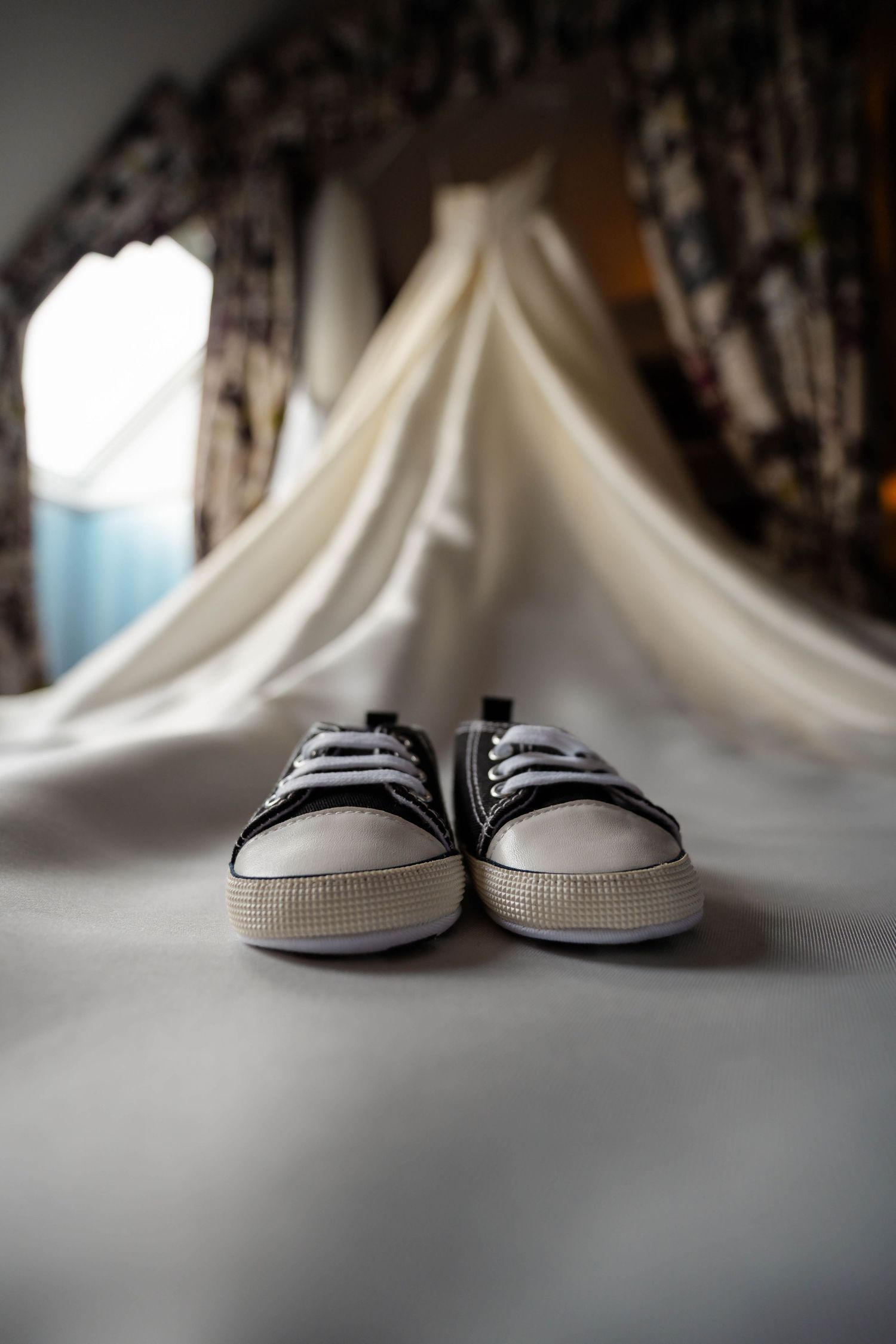 Black and white casual shoes photographed beneath a wedding dress hem.