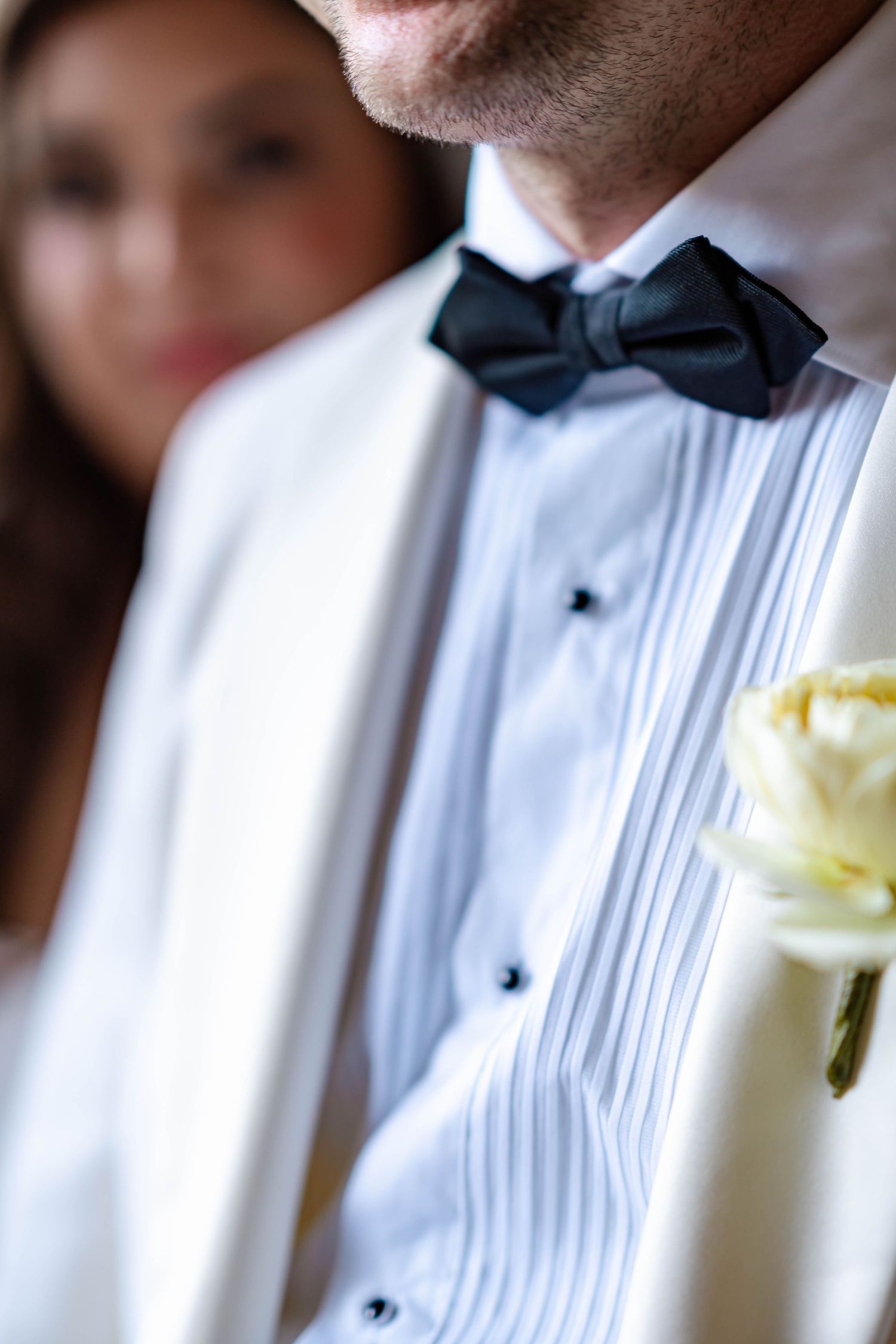 Row of groomsmen in white tuxedo shirts with pleated fronts and black bow ties at formal wedding event.