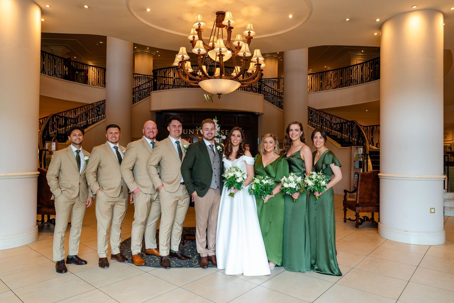 Panoramic view of a wedding party lineup in an elegant white pillared venue.