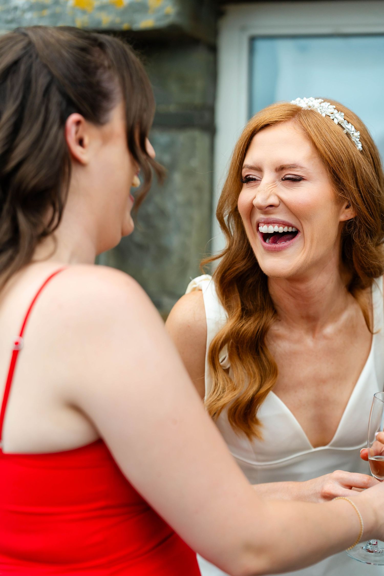 A group of friends in red dresses share laughter and champagne during a celebration.