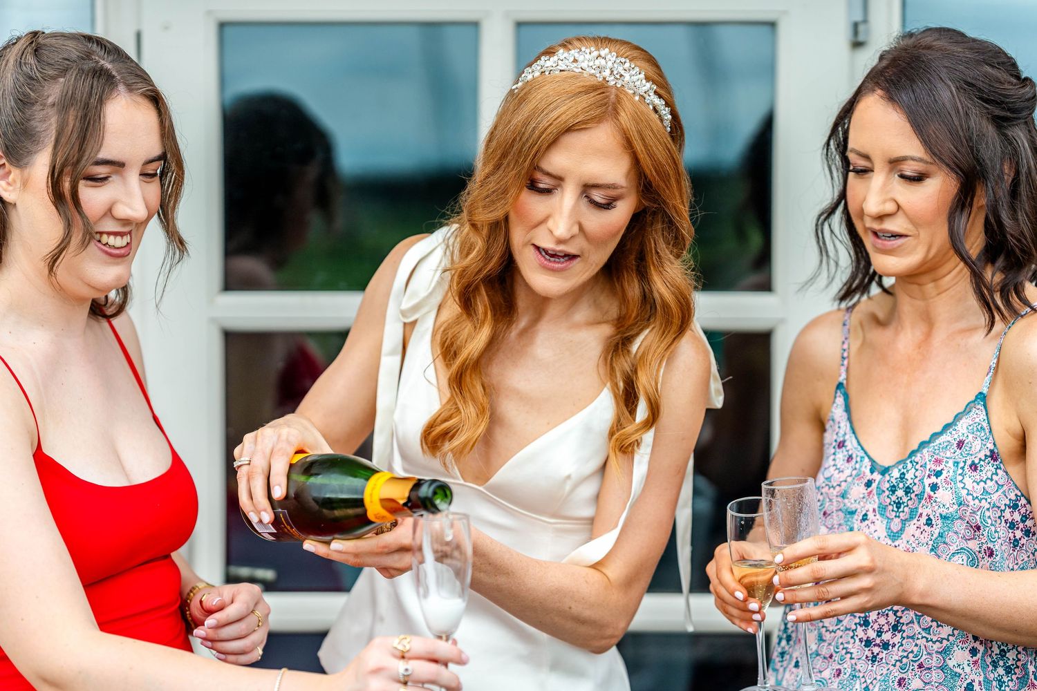 Wedding party in colorful dresses gathered together outdoors.