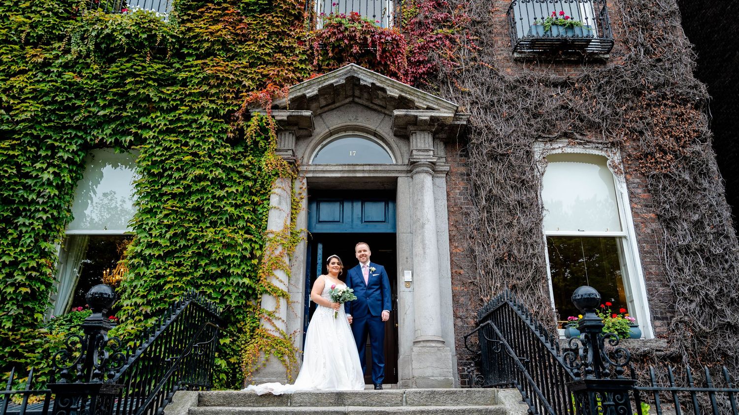 Wide angle view of historic building facade covered in red and green ivy.