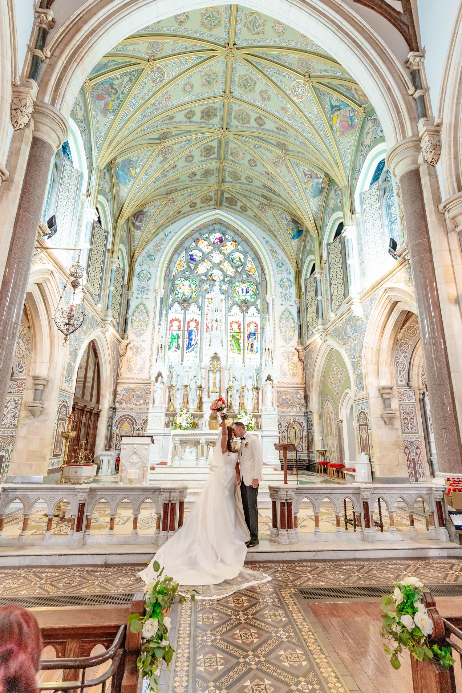 Beautiful cathedral interior with vaulted ceiling, stained glass windows and ornate Gothic architecture during a wedding ceremony.