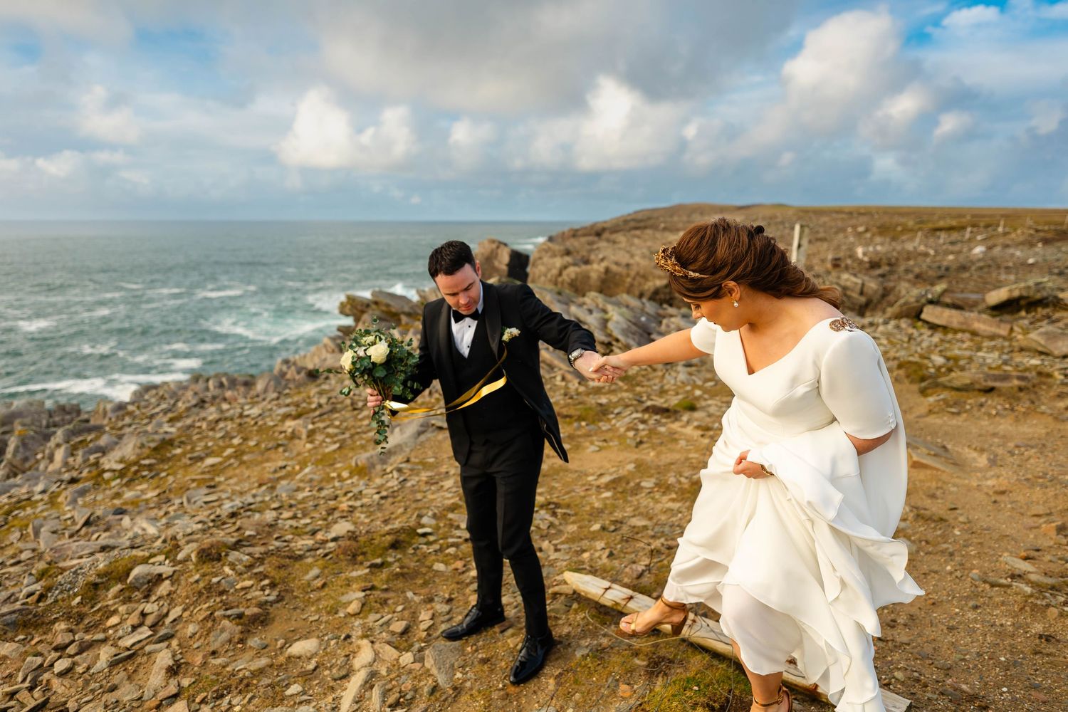 Coastal wedding photoshoot on dramatic rocky cliffs overlooking the ocean.