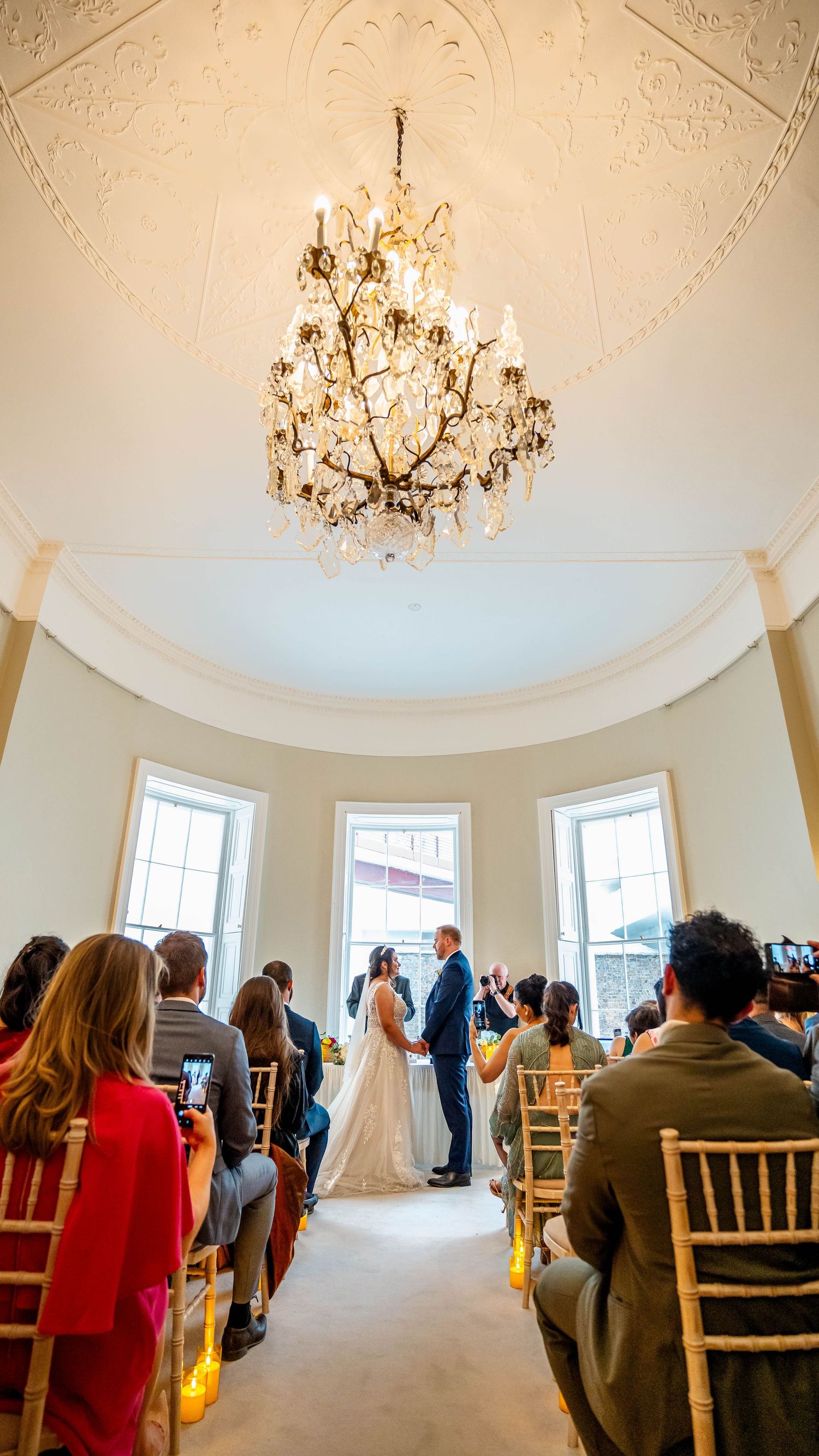 Ornate domed ceiling room with crystal chandelier during wedding ceremony.