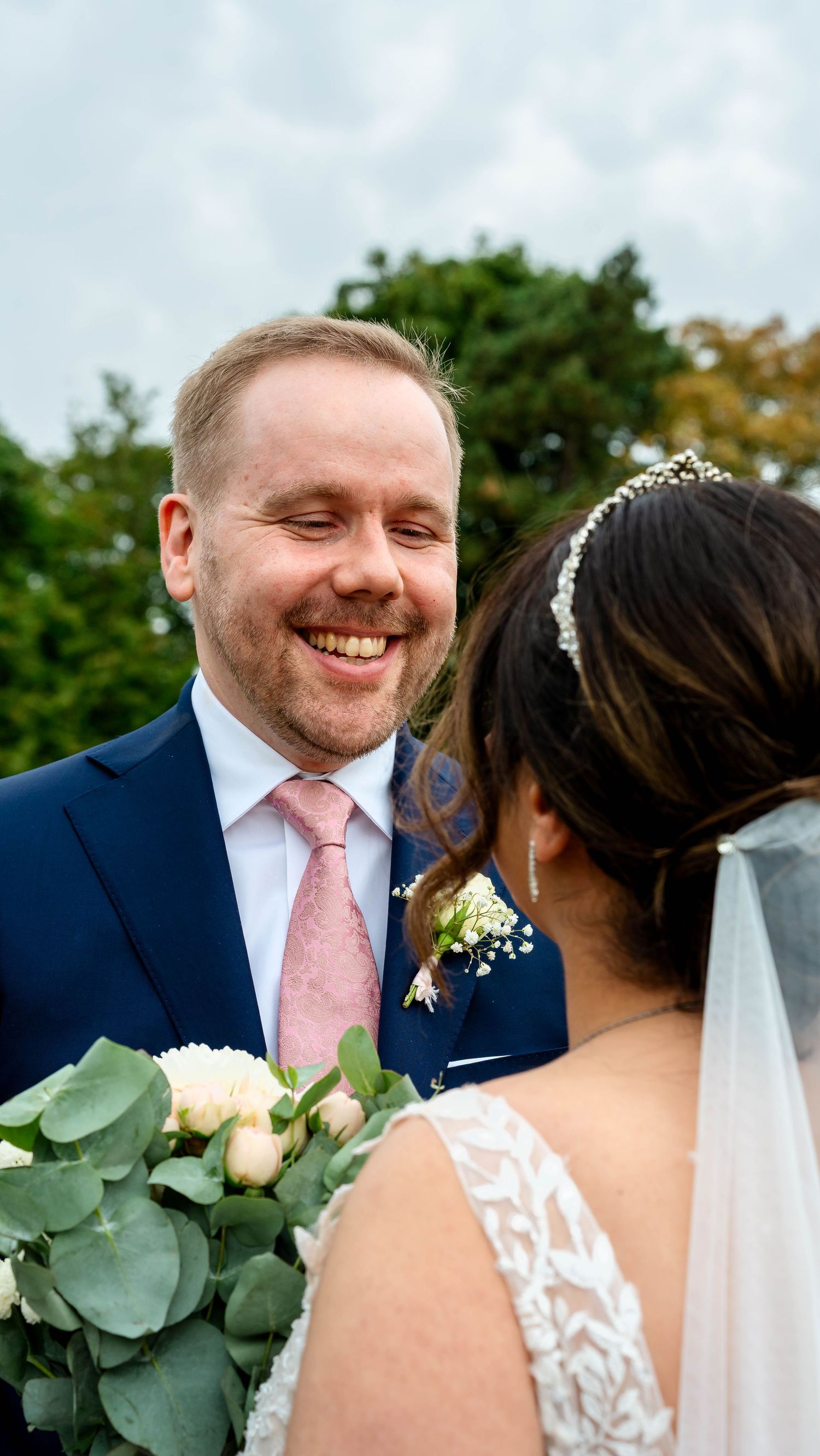 A couple shares a joyful moment in a garden setting with flowers and greenery.