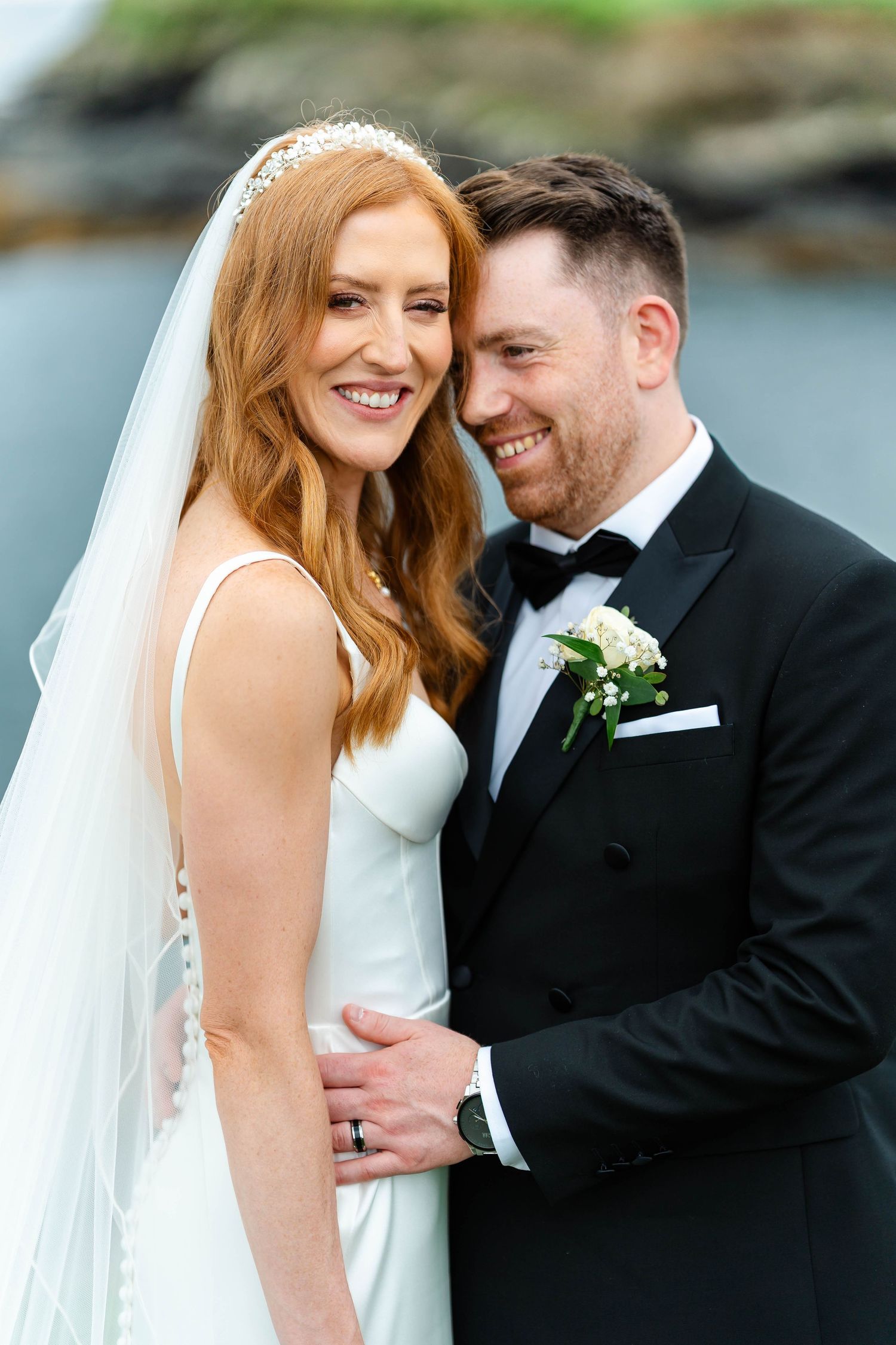Intimate wedding portraits captured along a rocky coastline with natural lighting and ocean views.