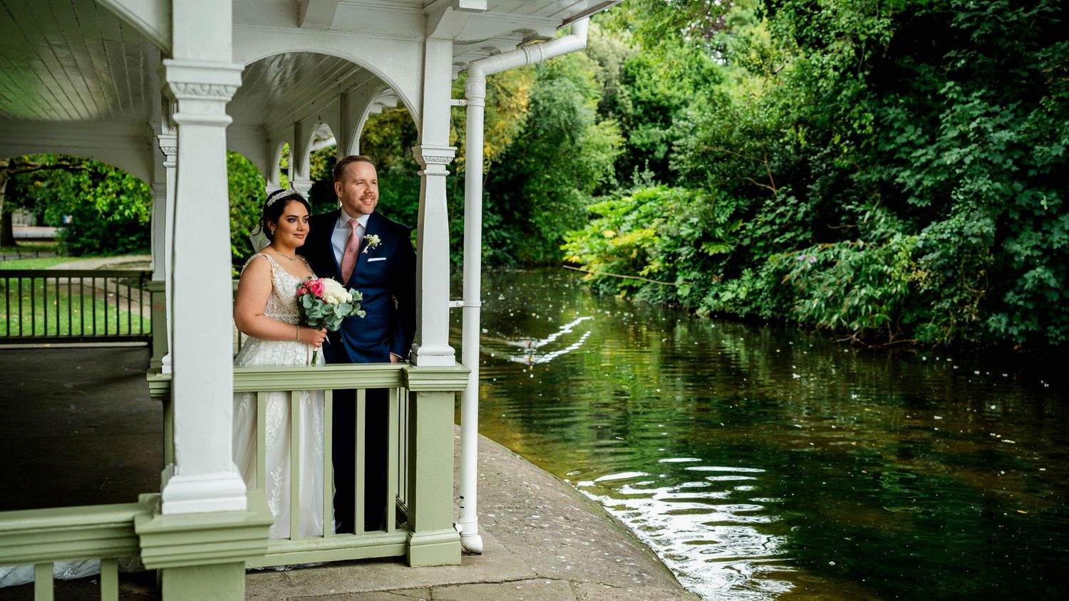 Long panoramic shot of a garden wedding venue with white pillars and water features.