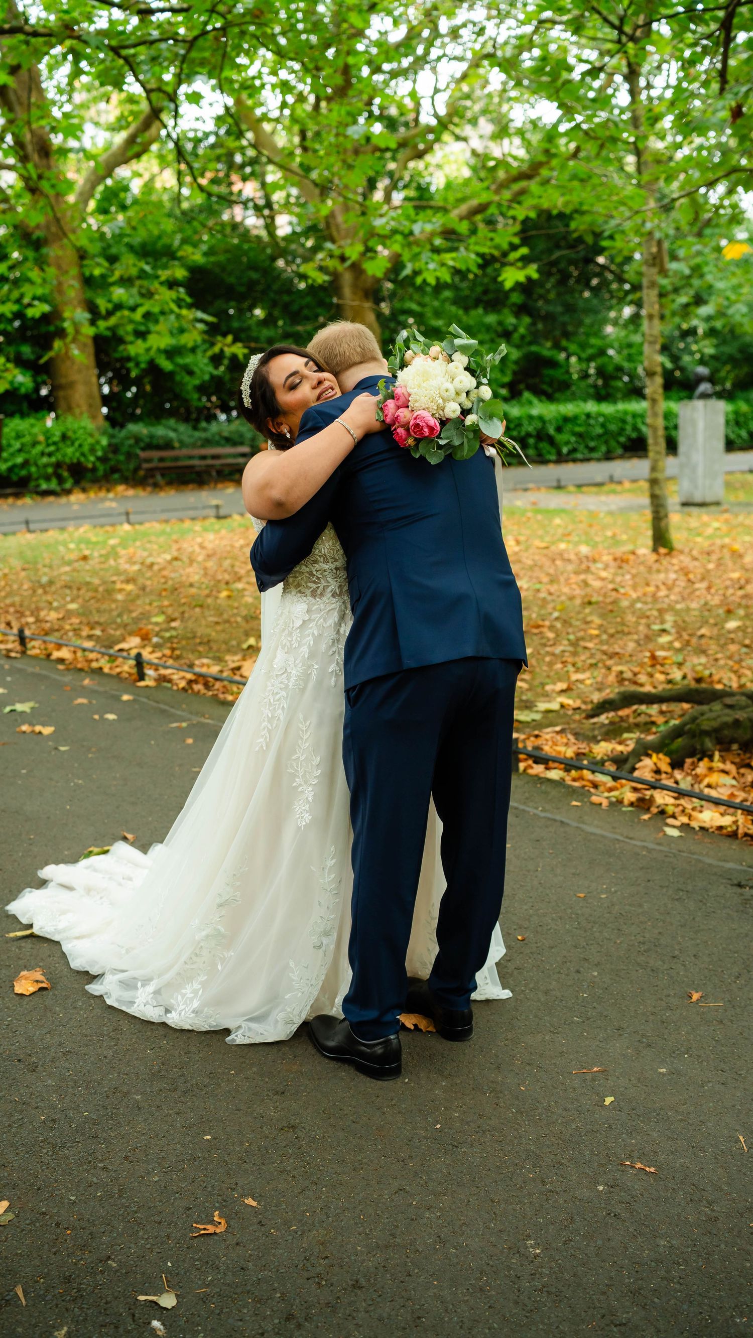 A romantic wedding couple dances and dips on a path covered in autumn leaves.