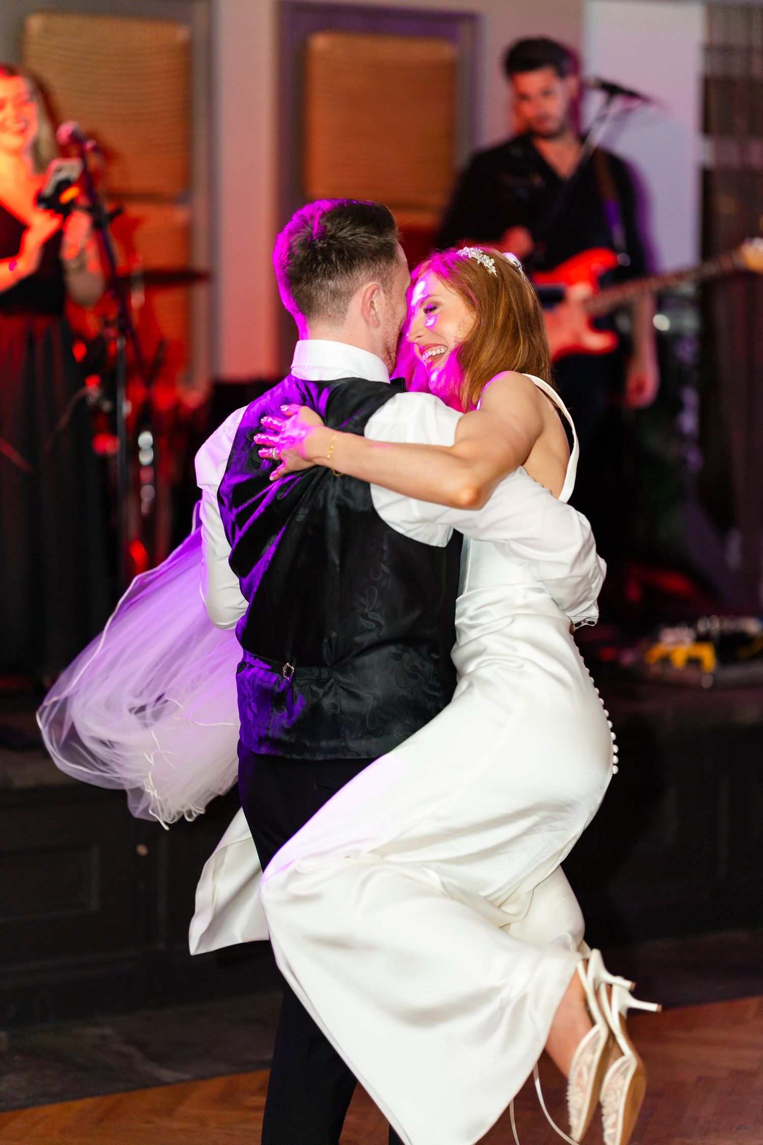 Newlyweds perform their first dance with dramatic purple lighting at their wedding reception.