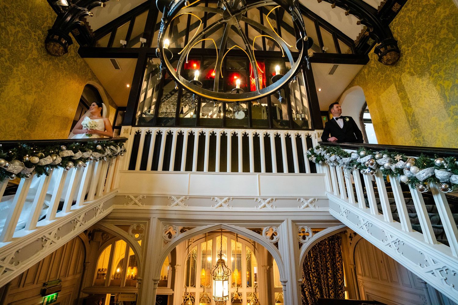A grand wedding venue with vaulted ceilings, chandeliers, and festive holiday decorations.