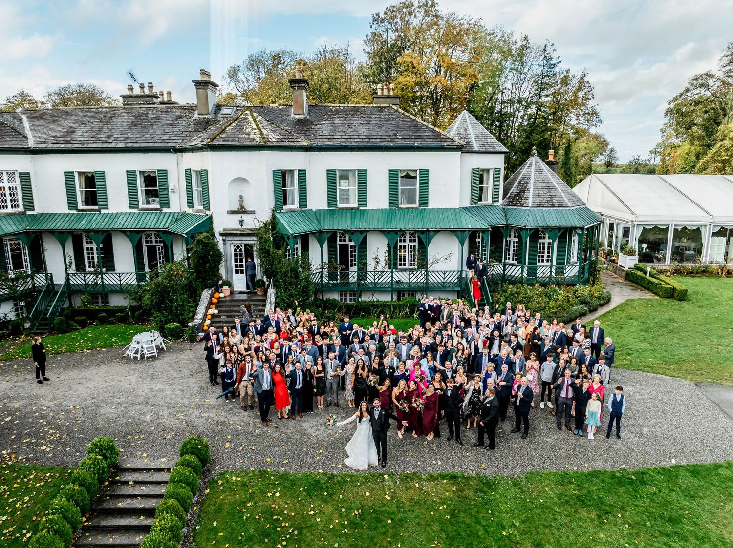 Panoramic view of guests gathered outside a historic manor house for a special event.