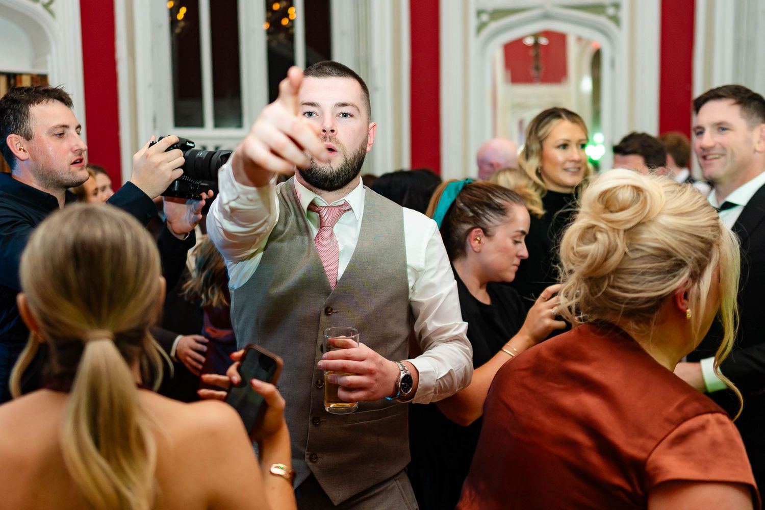 Guests enjoying themselves on a dance floor with elegant white decor and lighting in the background.