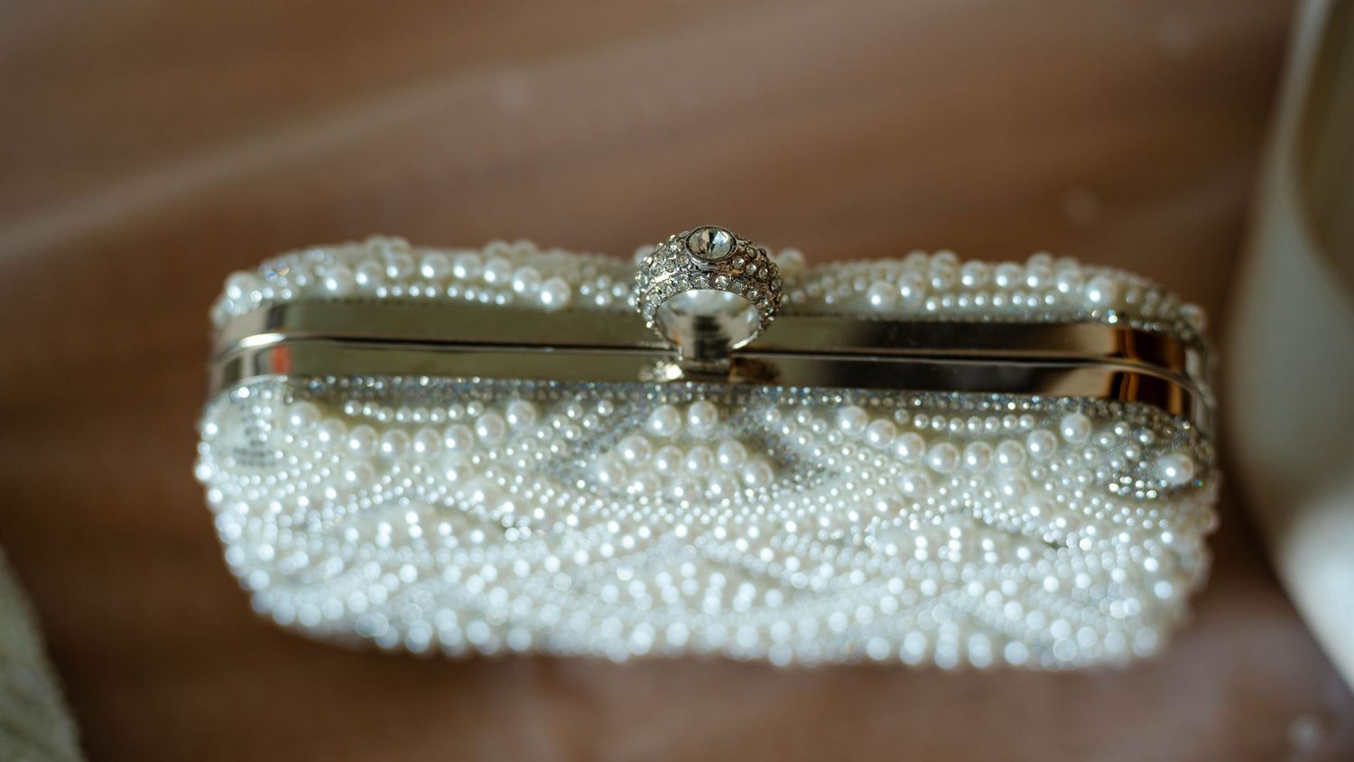 Detailed shot of pearl-encrusted bridal accessories against neutral background.