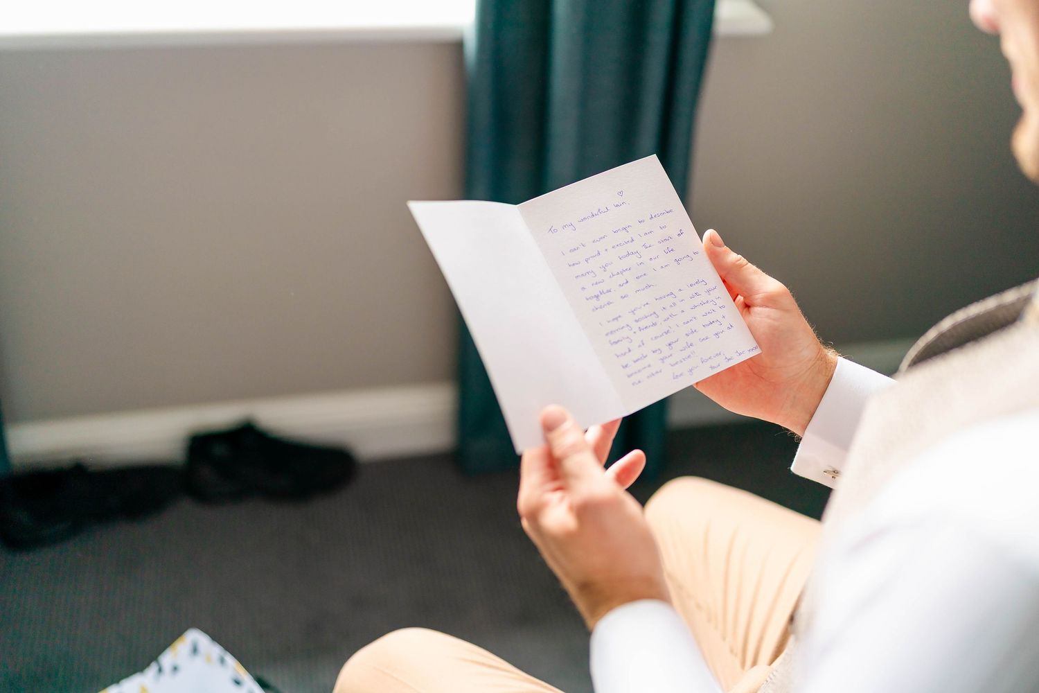 Person reading handwritten letter near window with natural lighting.