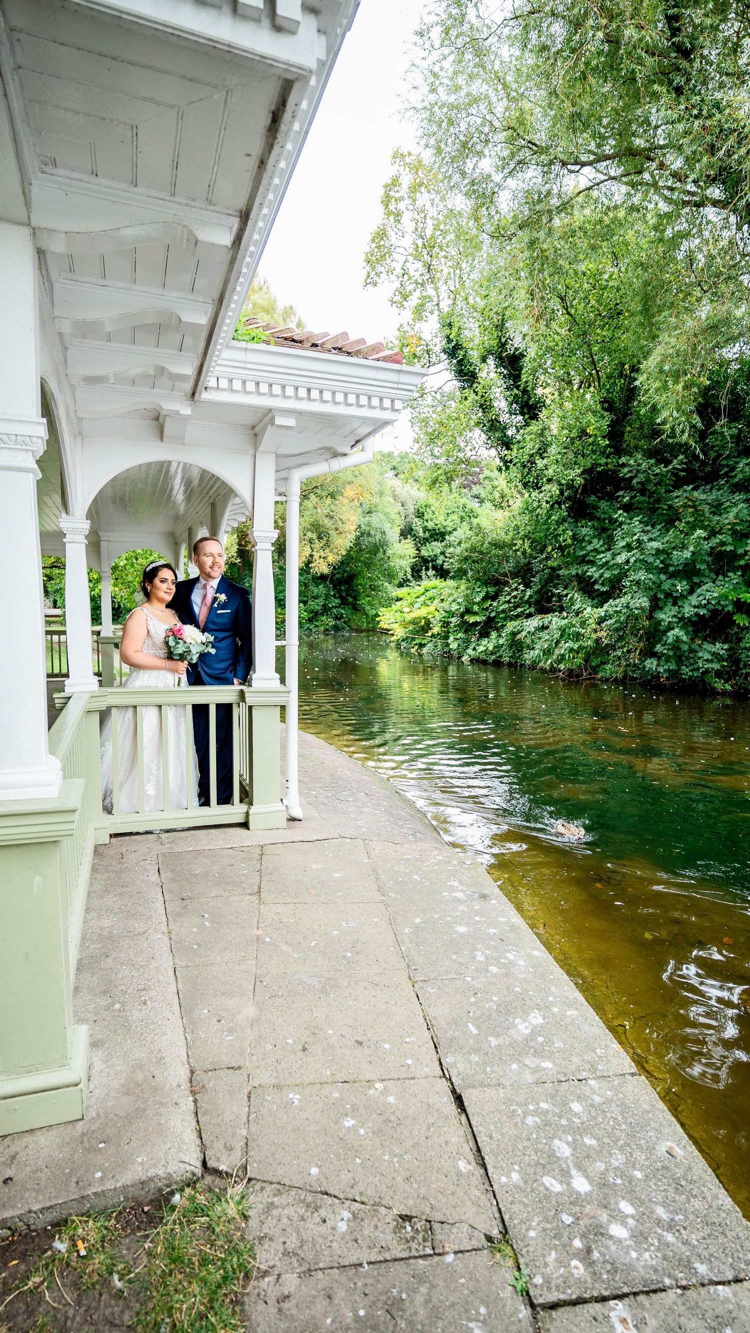 A white gazebo overlooking a serene pond creates a romantic wedding setting.