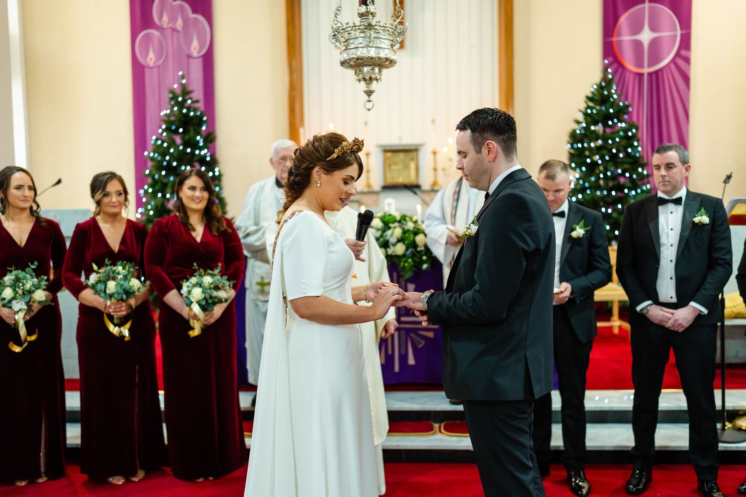Wedding party gathered at church altar with festive holiday decorations and purple accents.