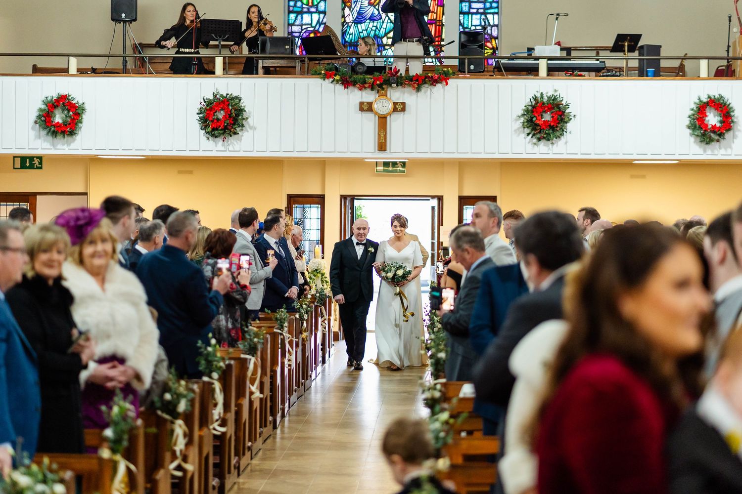 Wide view of church interior decorated with red poinsettias and Christmas garland.