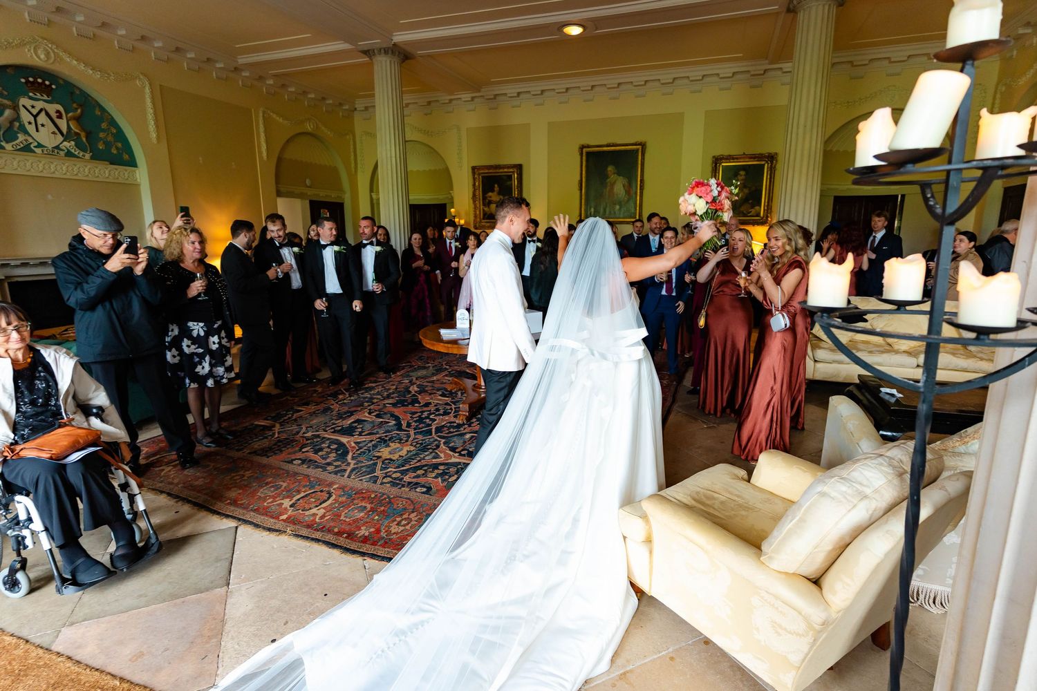 A panoramic view of an elegant wedding ceremony in a grand ballroom with ornate decor and flowing white dresses.