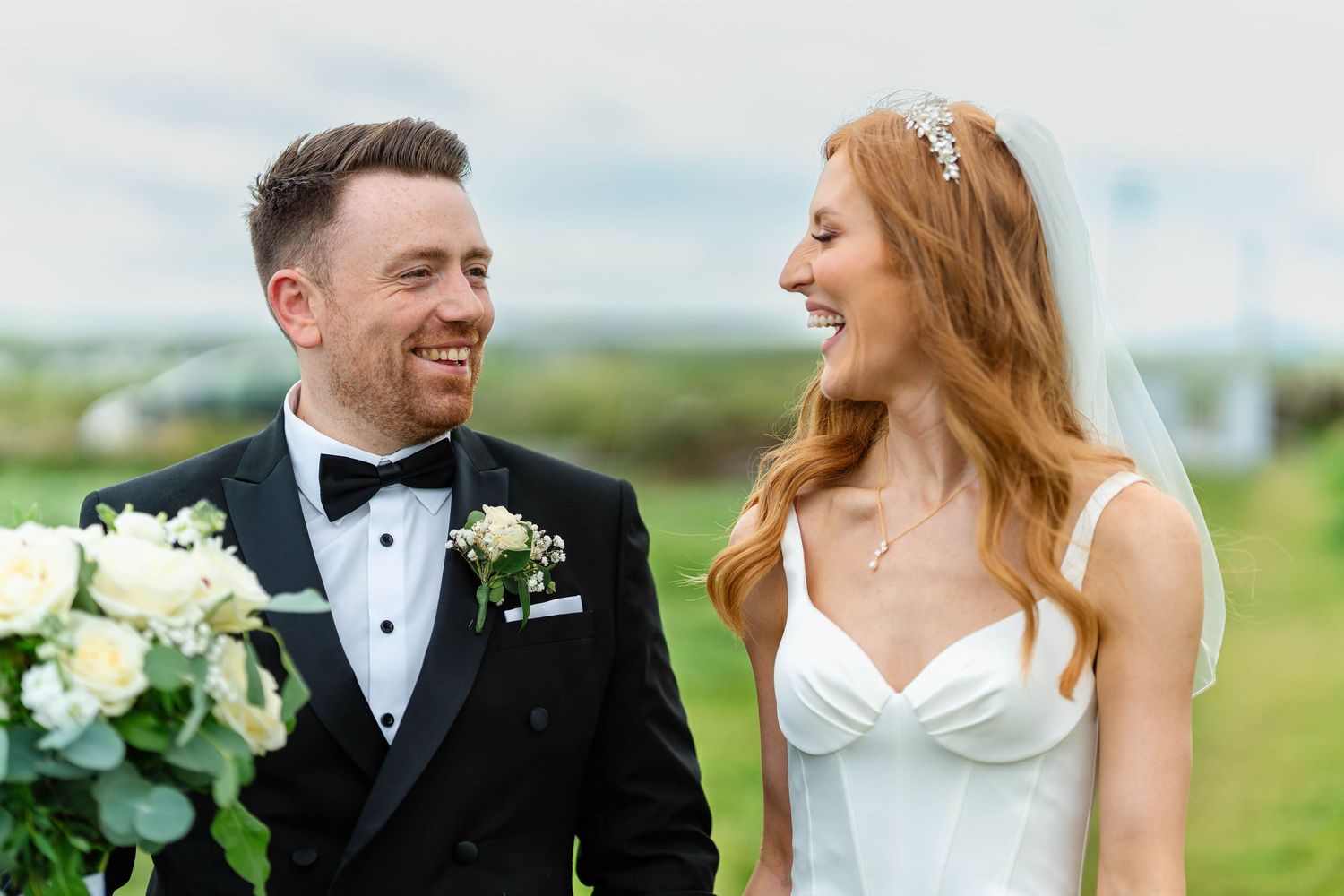 Candid moments of joy between a couple in wedding attire against a cloudy coastal backdrop.