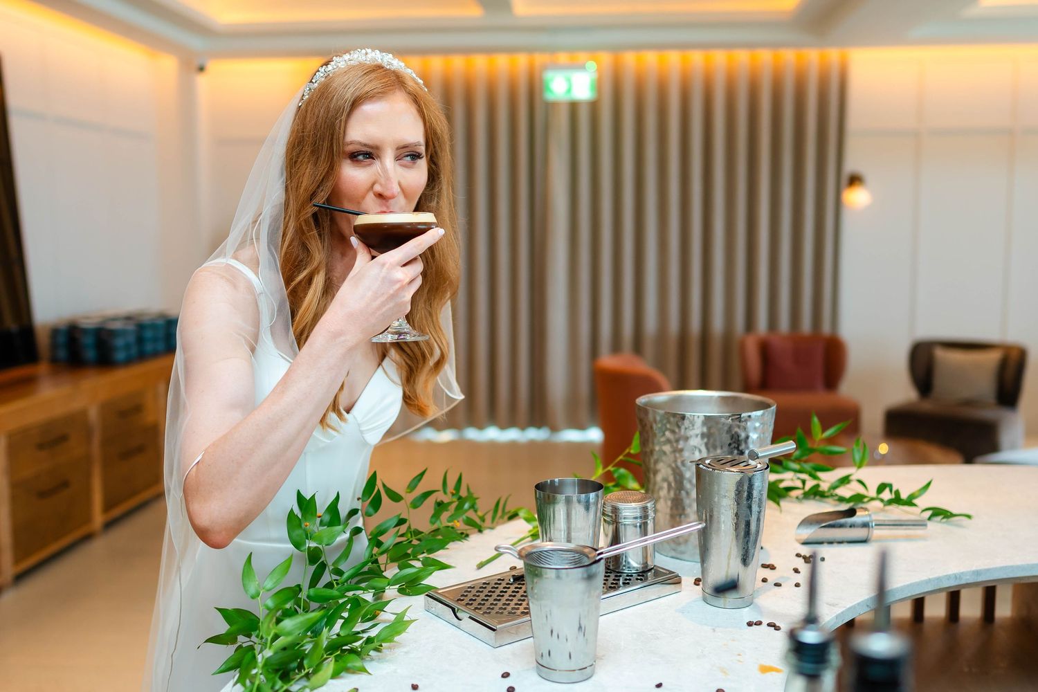 A person in a wedding dress sips a drink at an elegant reception table.