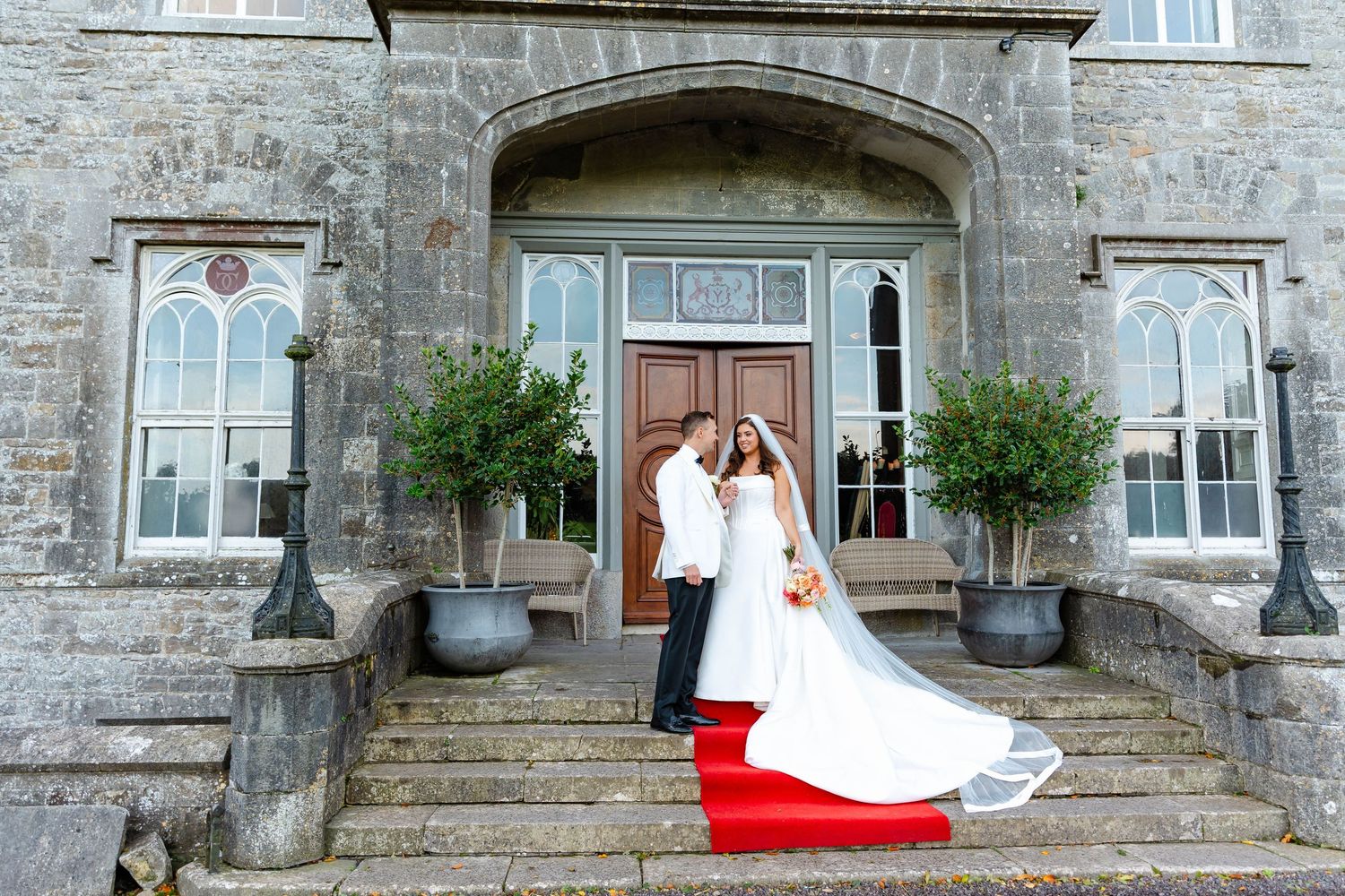 Wedding couple poses in front of historic stone building with arched doorways and windows in romantic photo sequence.