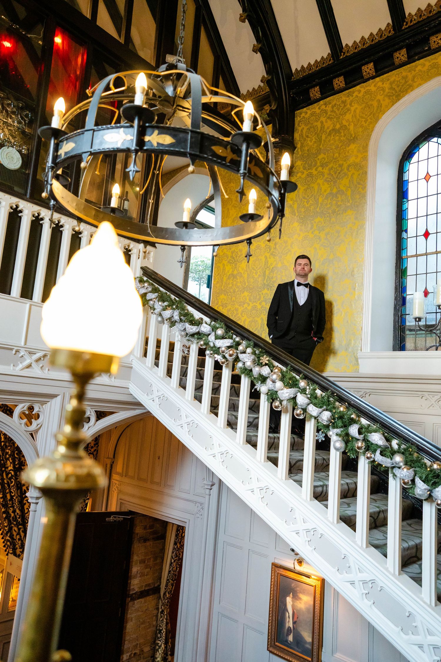 Elegant interior staircase with ornate wood trim and stained glass windows.