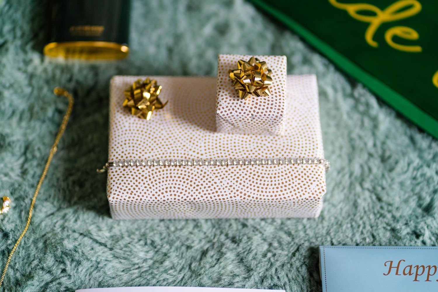 Elegant wedding rings and accessories arranged on a textured white surface with green accents.