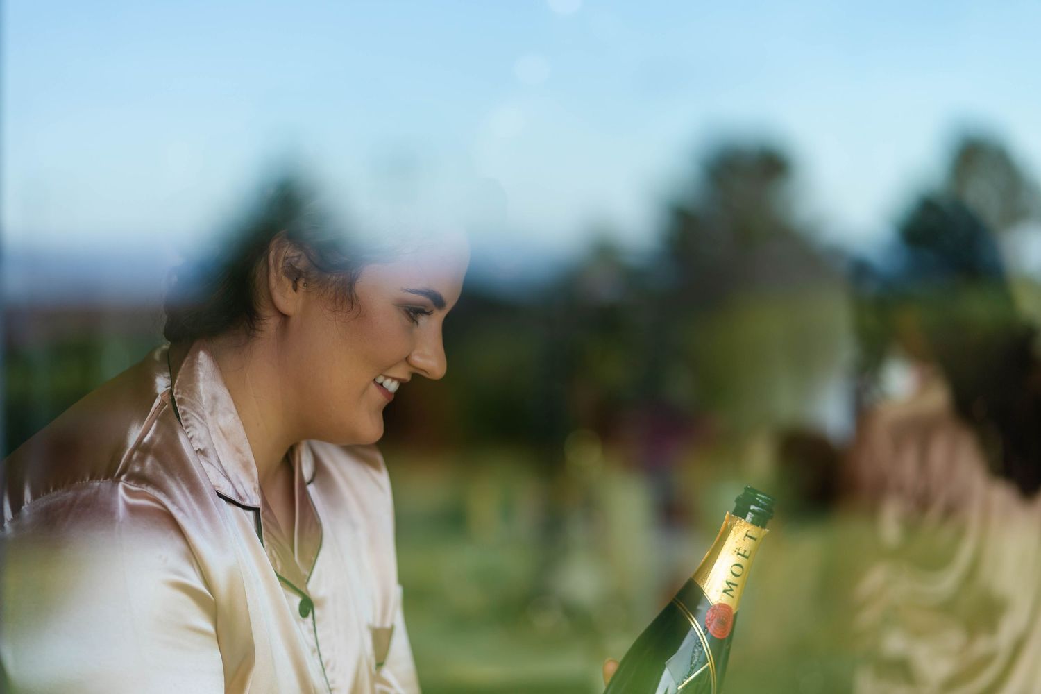 Person enjoying champagne outdoors in soft focus with natural lighting.