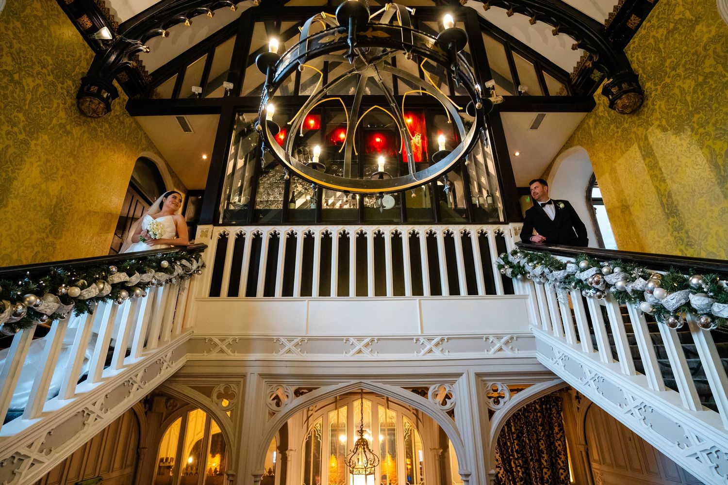 A historic venue's decorated staircase and balcony with ornate architectural details and holiday garland.