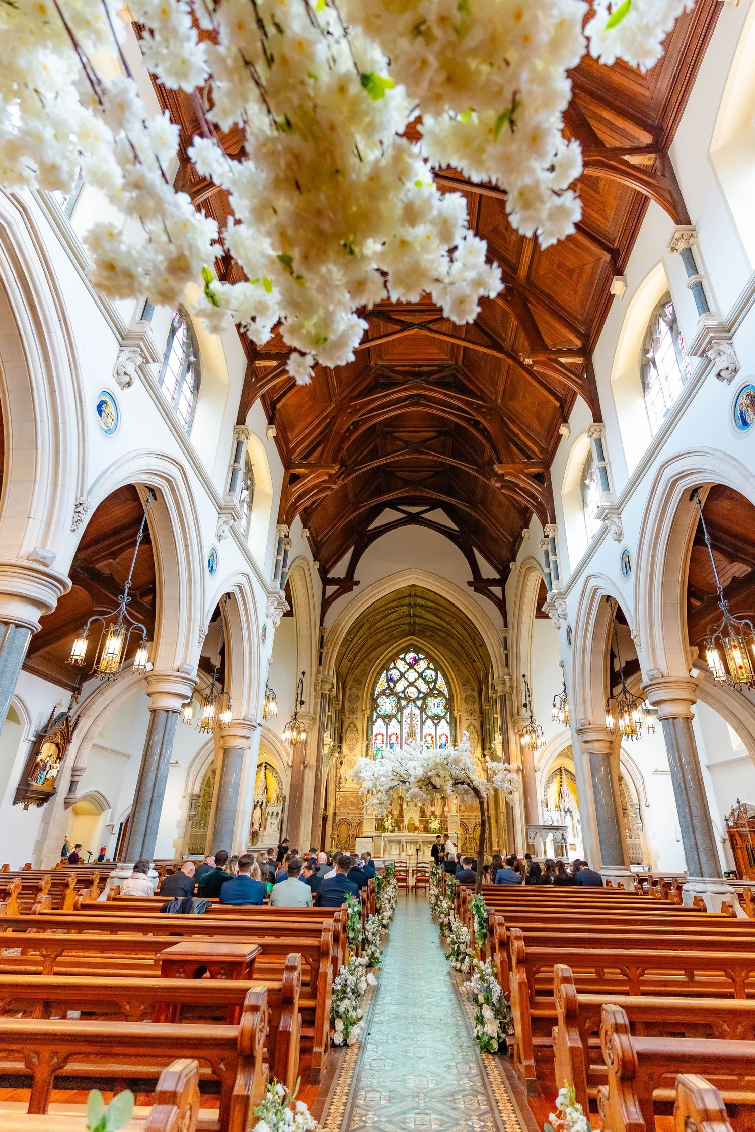 Beautiful church interior decorated with white cherry blossoms along the aisle for a wedding ceremony.