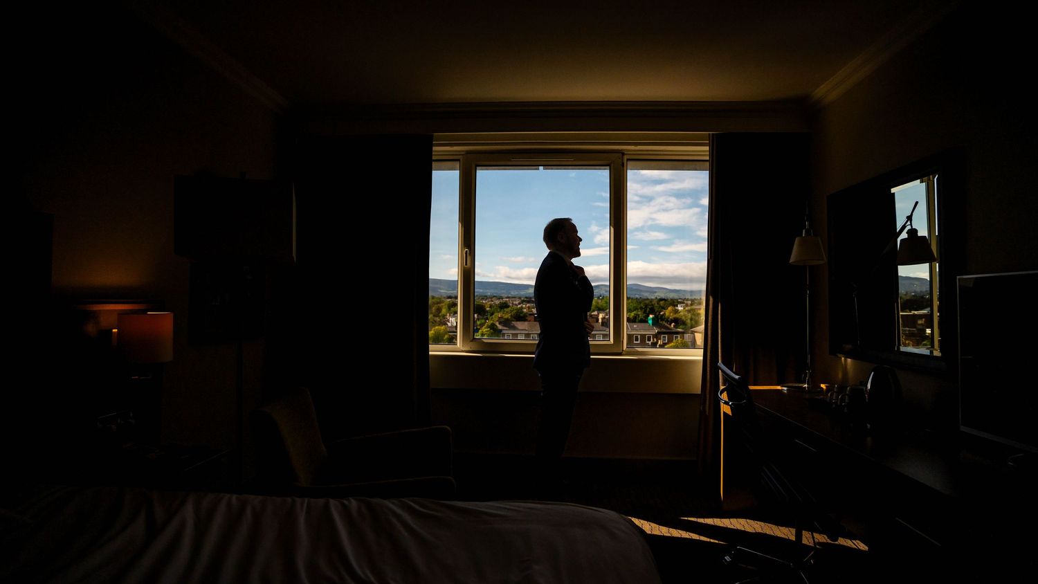 Dark interior room with bright window showing scenic mountain landscape view.