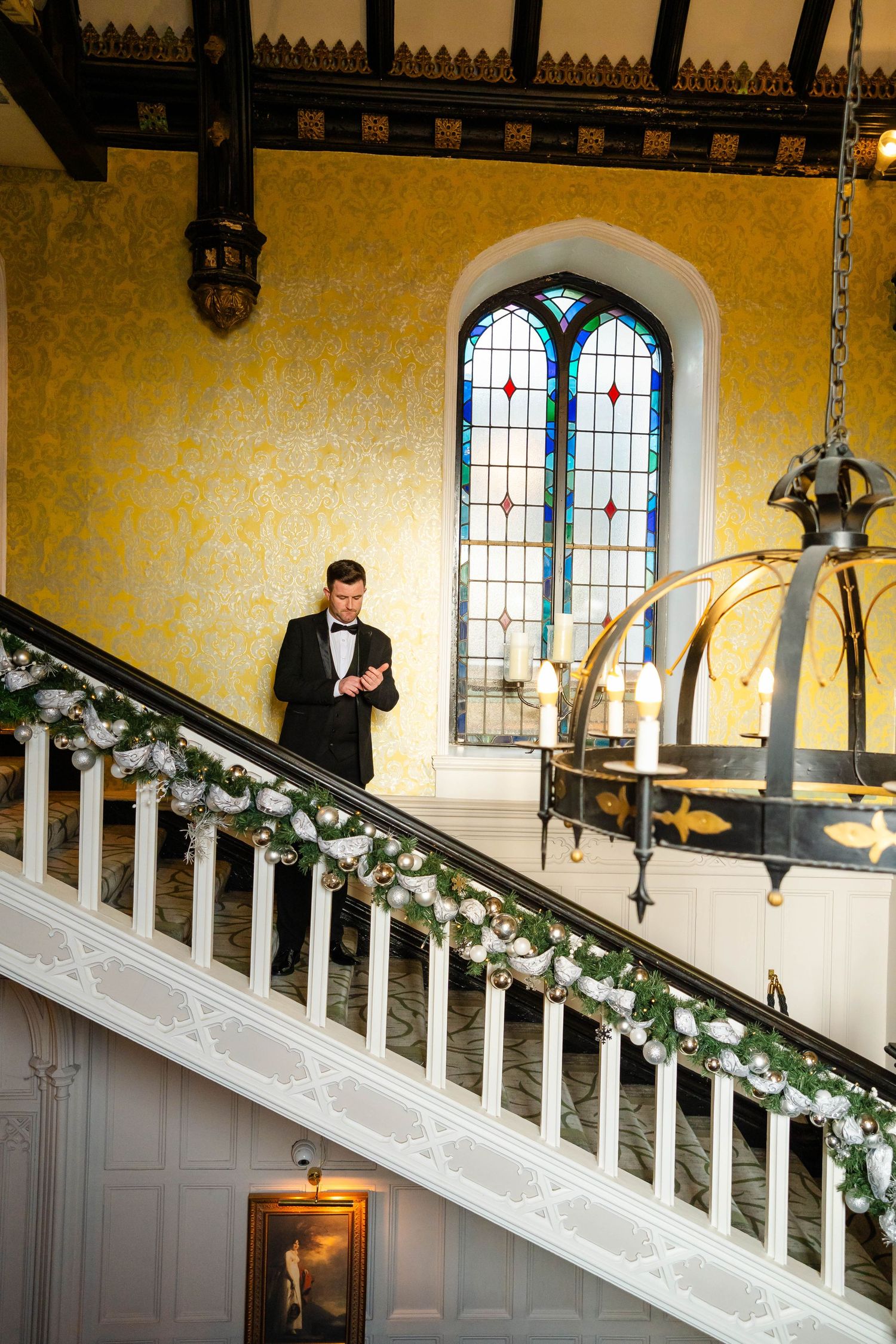 Grand staircase decorated with white garland and holiday decorations in a historic building.