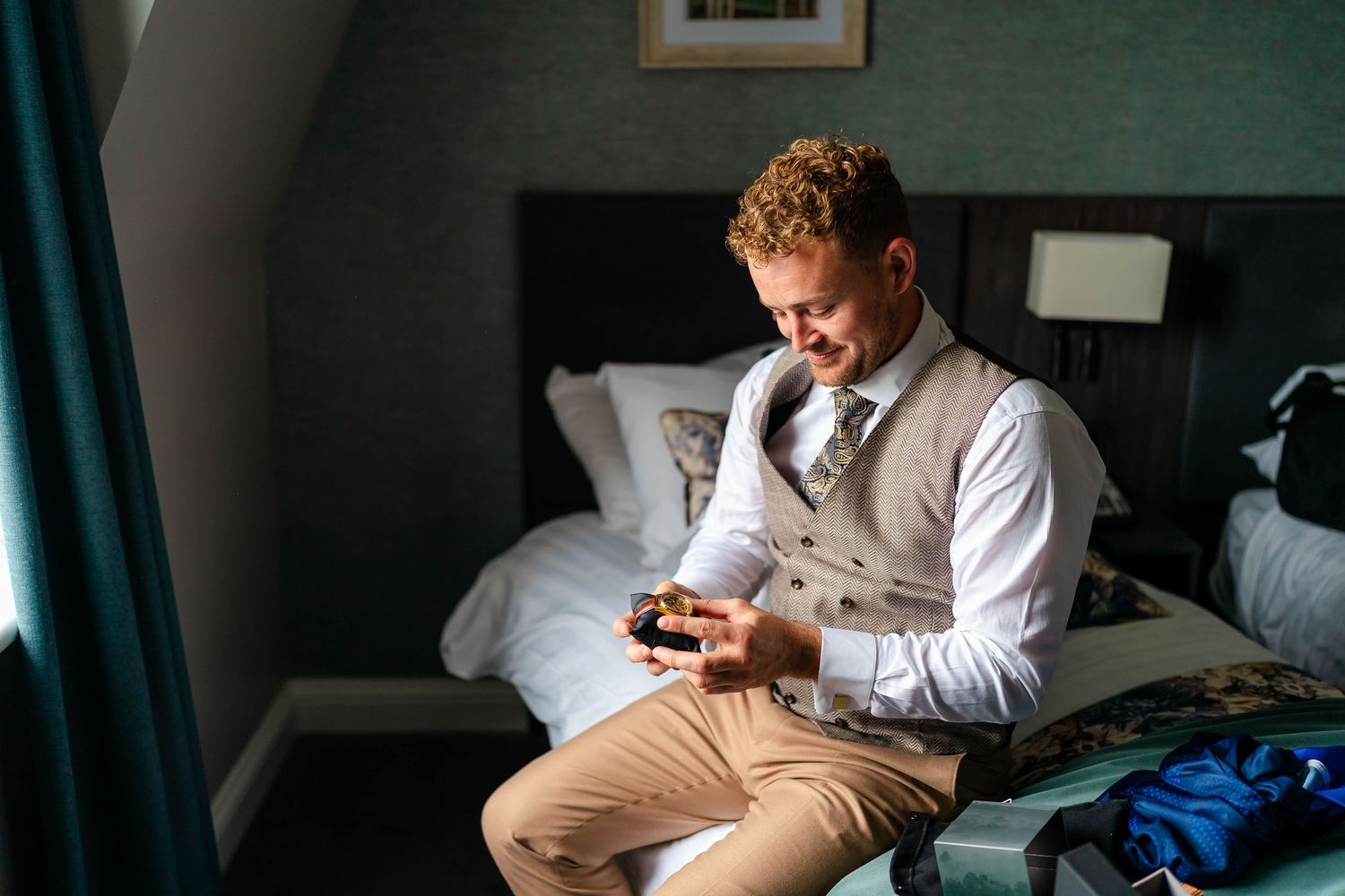 Person in formal attire reads emotional letter by window in hotel room.