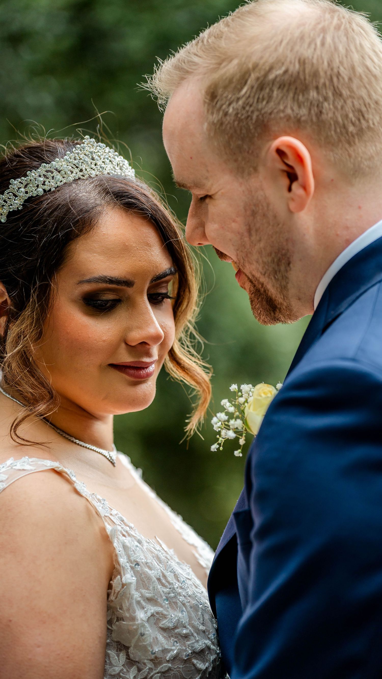 Close-up wedding portraits showing tender moments between newlyweds against a green outdoor backdrop.
