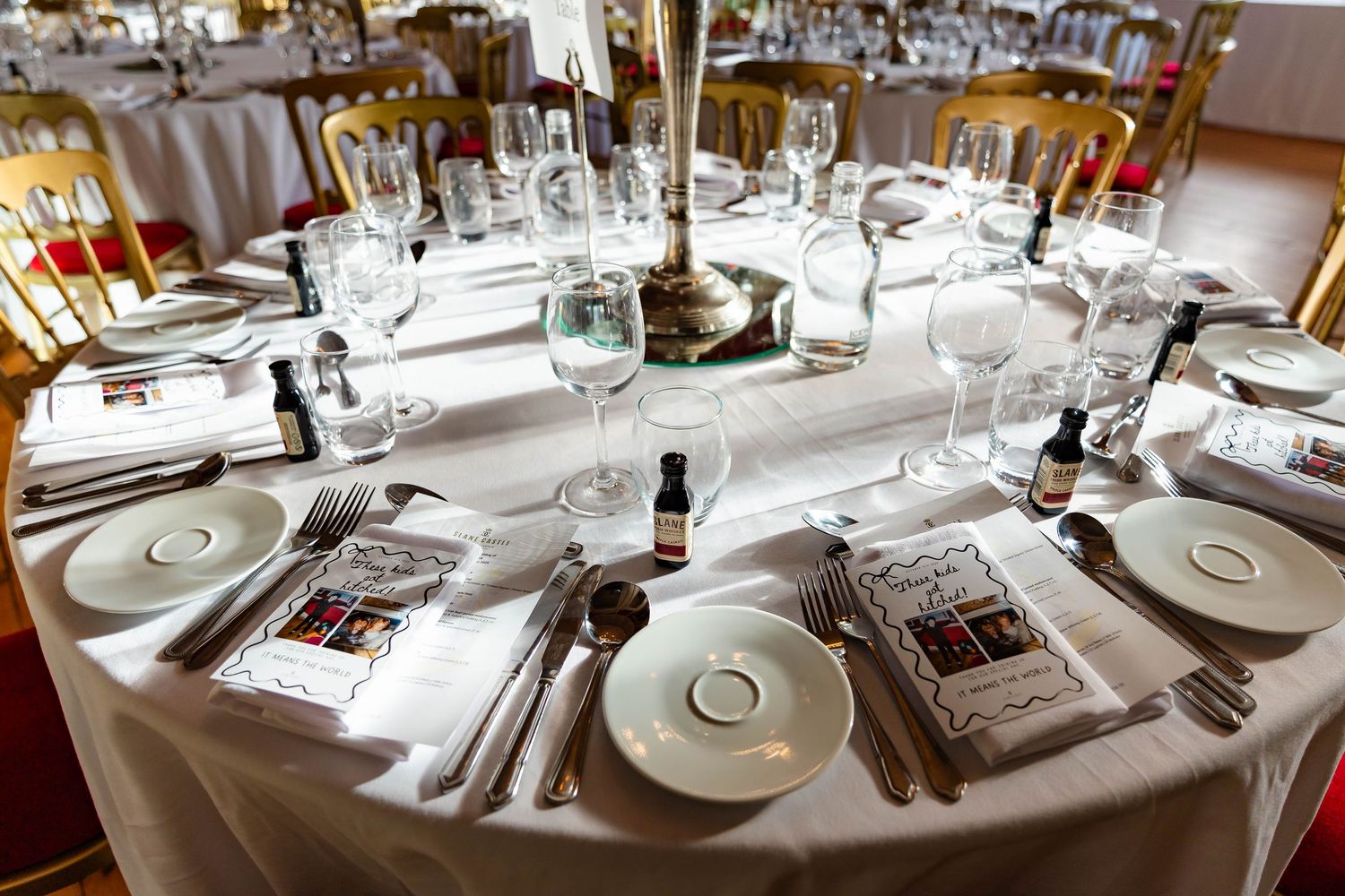 Elegant table settings with white linens, silver cutlery and wine glasses in an upscale restaurant dining room.