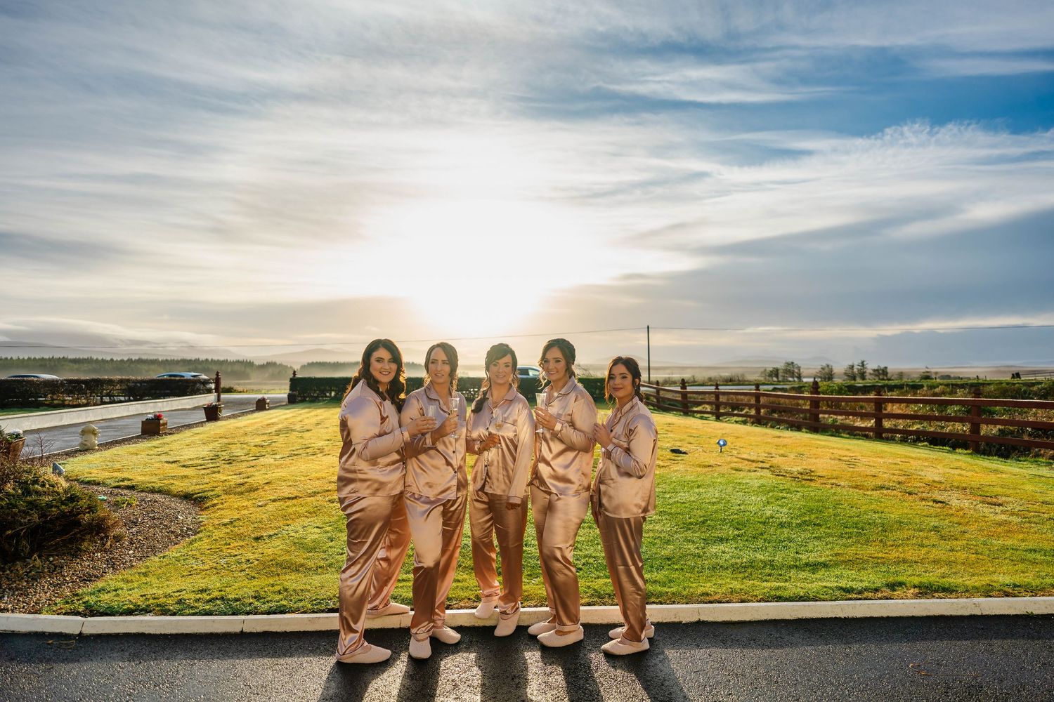 Wedding party arranged in formation on a hilltop against a dramatic sky backdrop.
