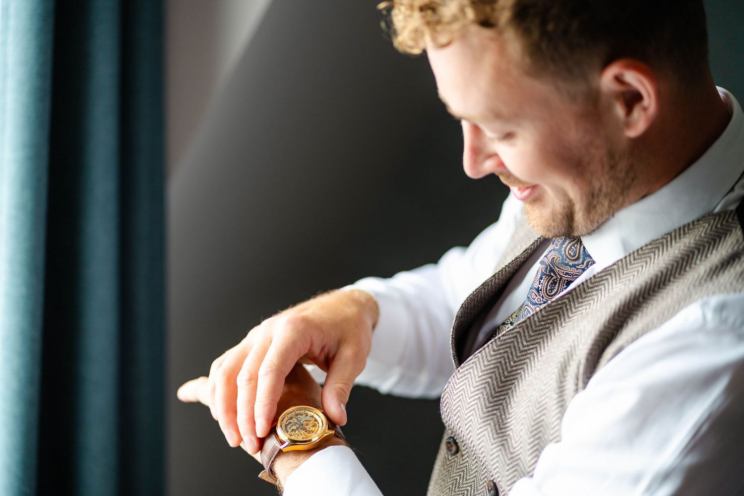 Person in formal attire checking gold watch on wrist.