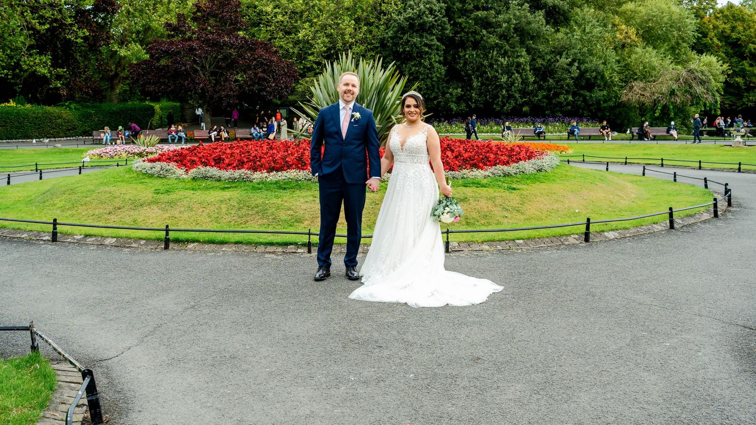 Wide angle view of a wedding couple walking through a beautifully landscaped park.