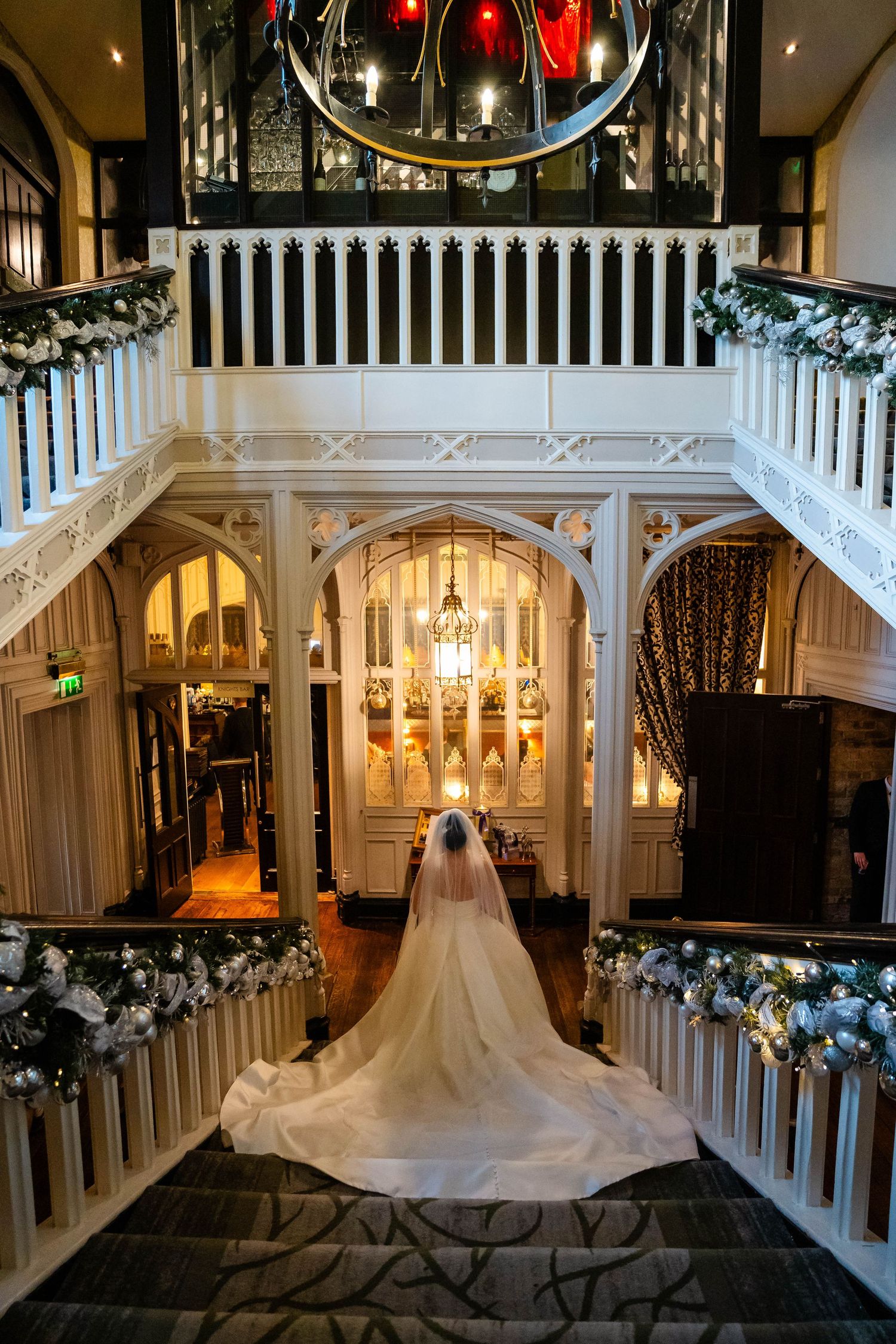 Elegant wedding venue with white pillars, chandeliers and decorative garlands creating a romantic atmosphere.