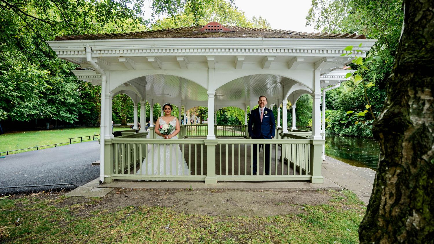 White gazebo surrounded by lush green trees in a scenic park setting.